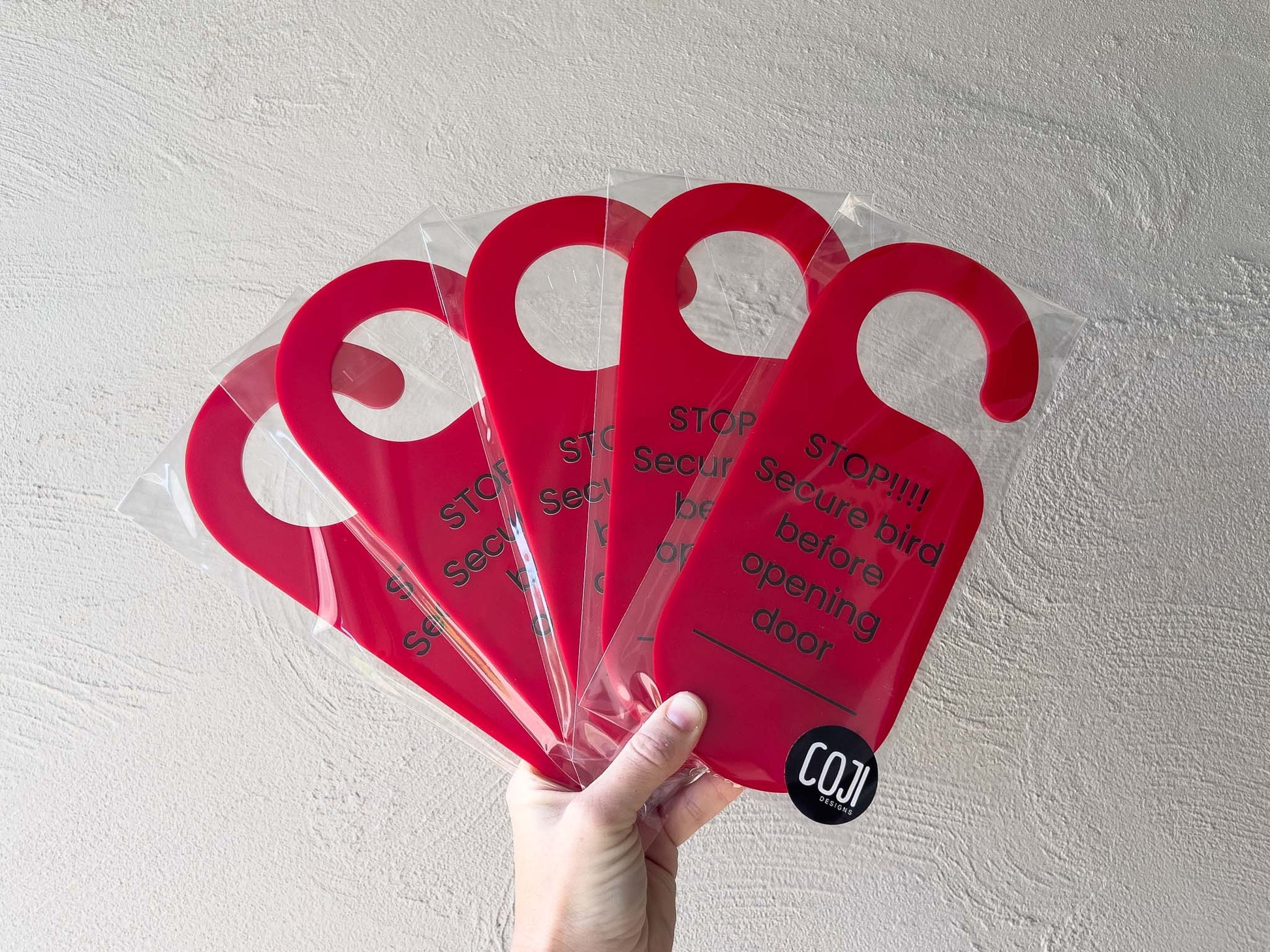 5 custom printed acrylic door hangers in red with black text that reads 'STOP!!!! Secure bird before opening door'.