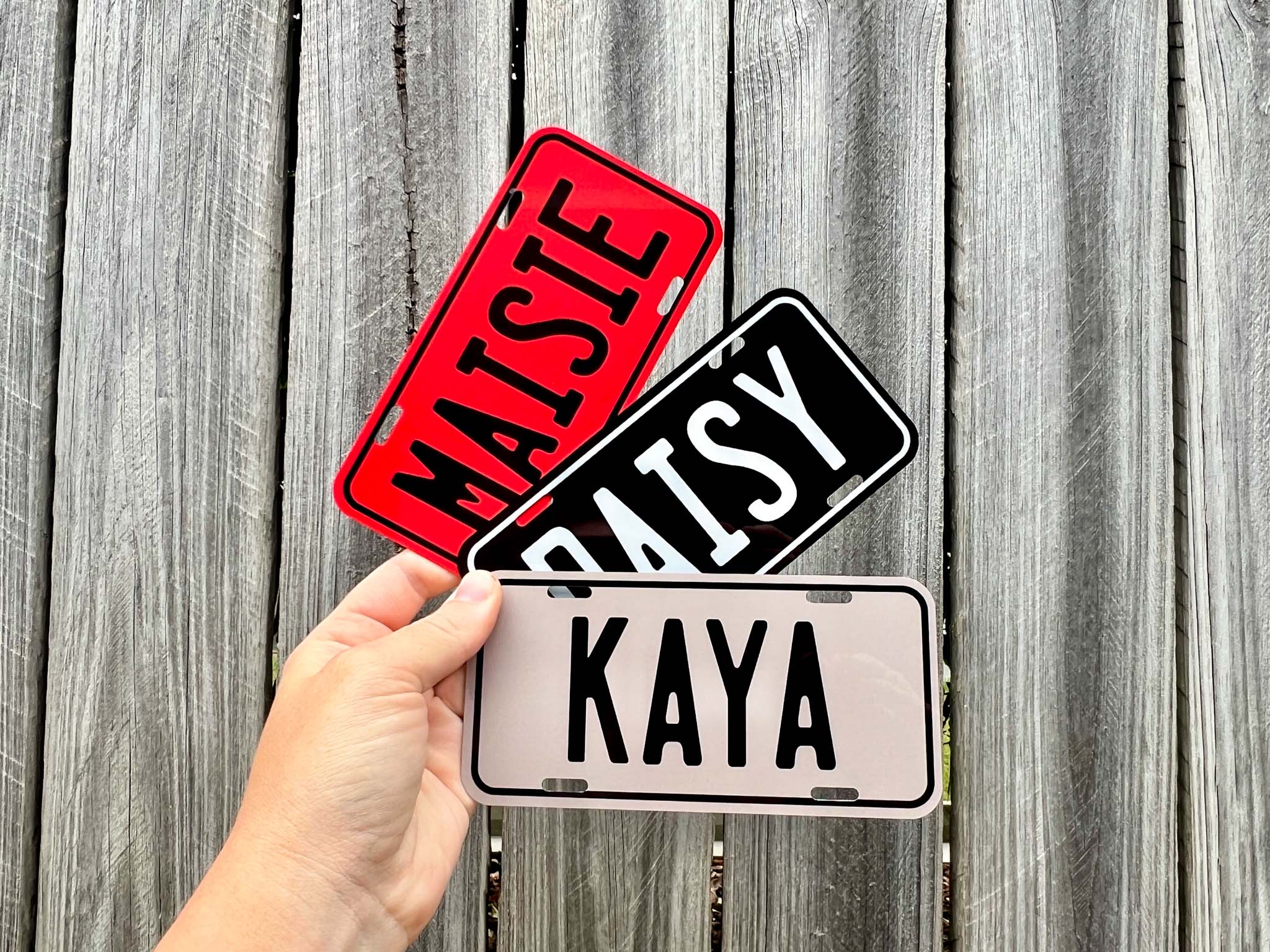 Three name plates labeled 'MAISTE', 'DAISY', and 'KAYA' held against a wooden background.
