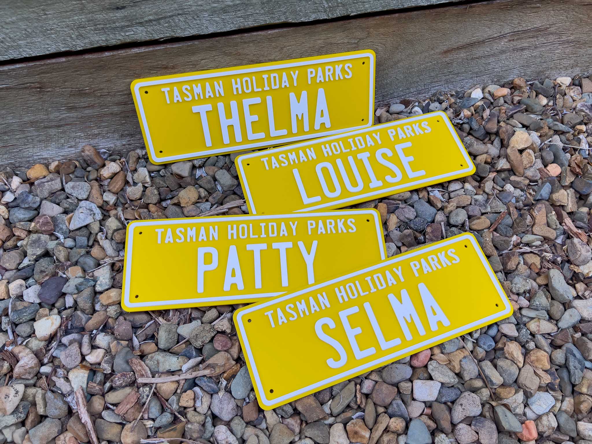 Four outdoor custom acrylic plates with the names 'Patty', 'Selma', Thelma' & 'Louise', in yellow and white.