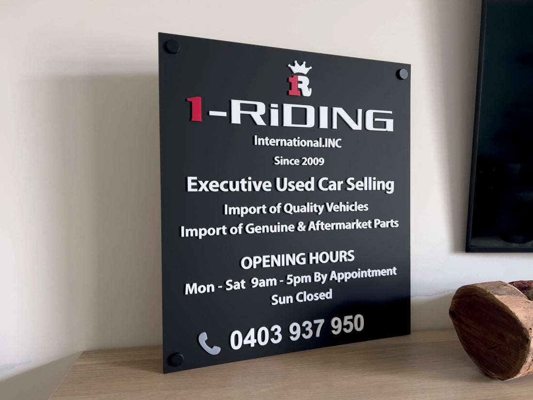Black signboard with white text displaying contact information for 1-Riding International, Inc.