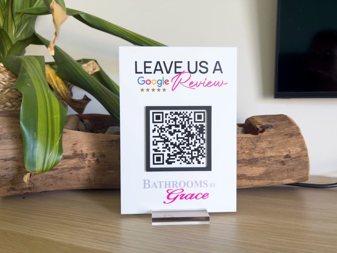 QR code sign on a stand with 'Leave Us a Google Review' for 'Bathrooms by Grace'.
