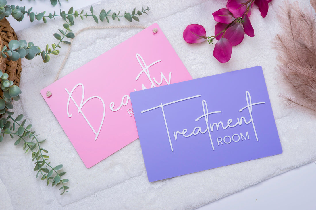 Two signs, one pink and one purple, with 'Beauty' and 'Treatment Room' text on a textured surface with decorative elements.
