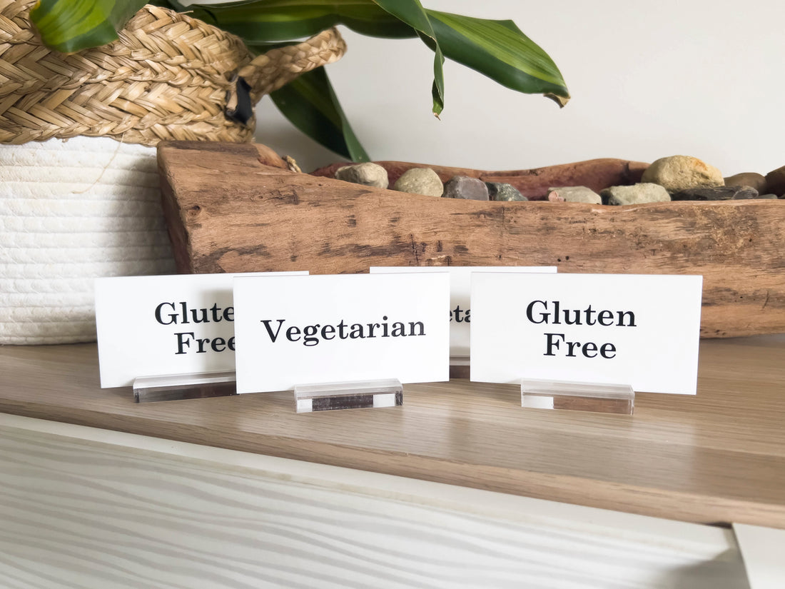 Three acrylic table signs indicating dietary preferences on a wooden surface with a decorative background.