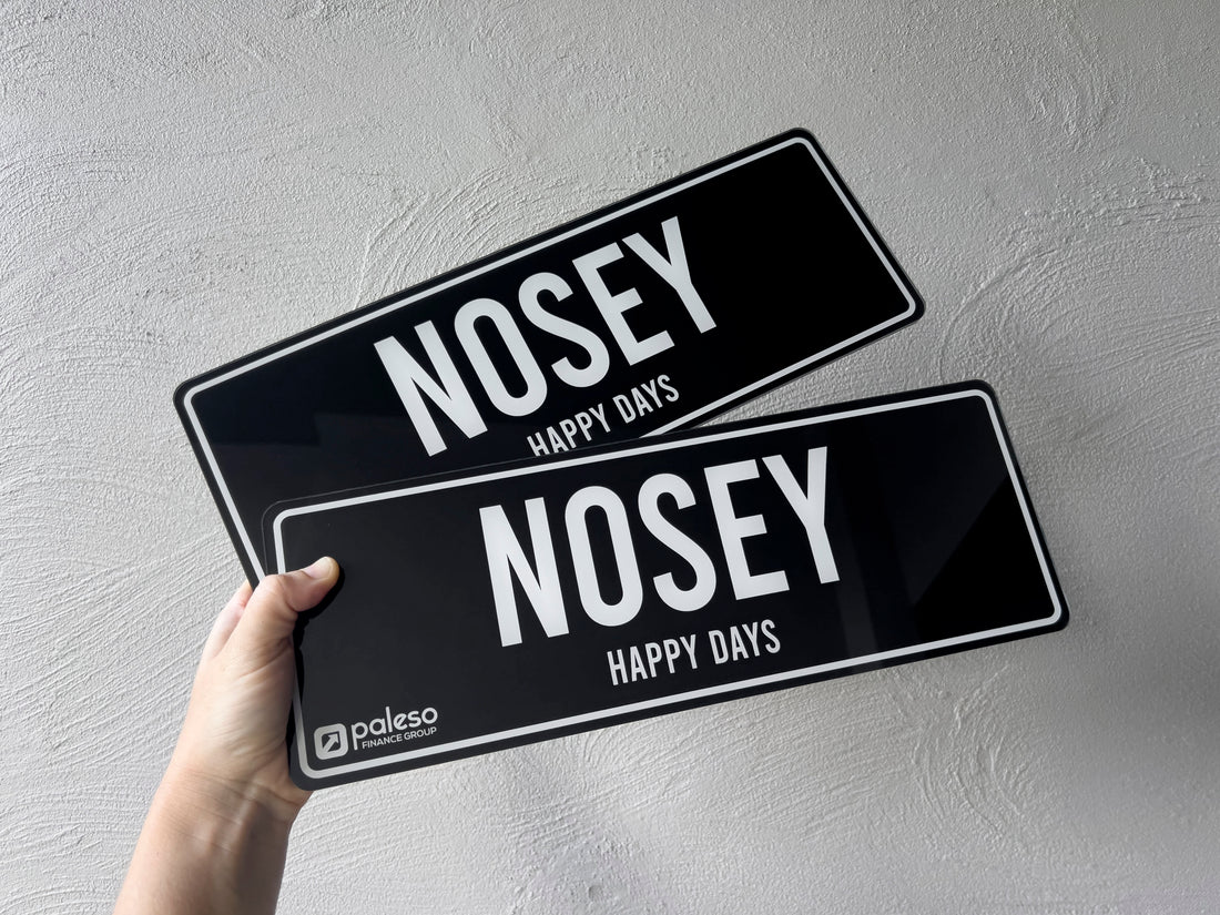 Two black and white custom printed novelty number plates for a retirement golf cart that read 'NOSEY HAPPY DAYS'.