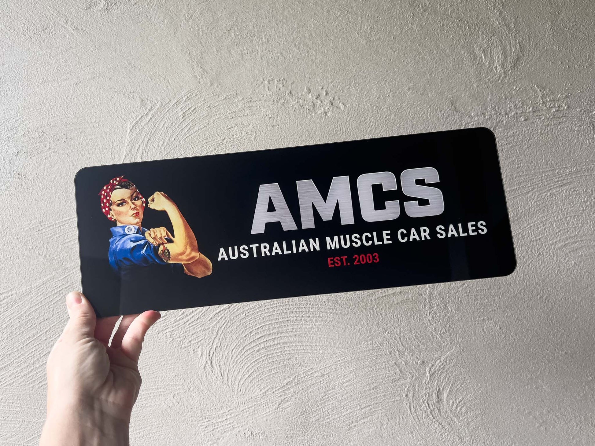 A custom printed logo plate with a clear acrylic overlay with a logo & text that reads 'AMCS Australian Muscle Car Sales Est. 2003'.