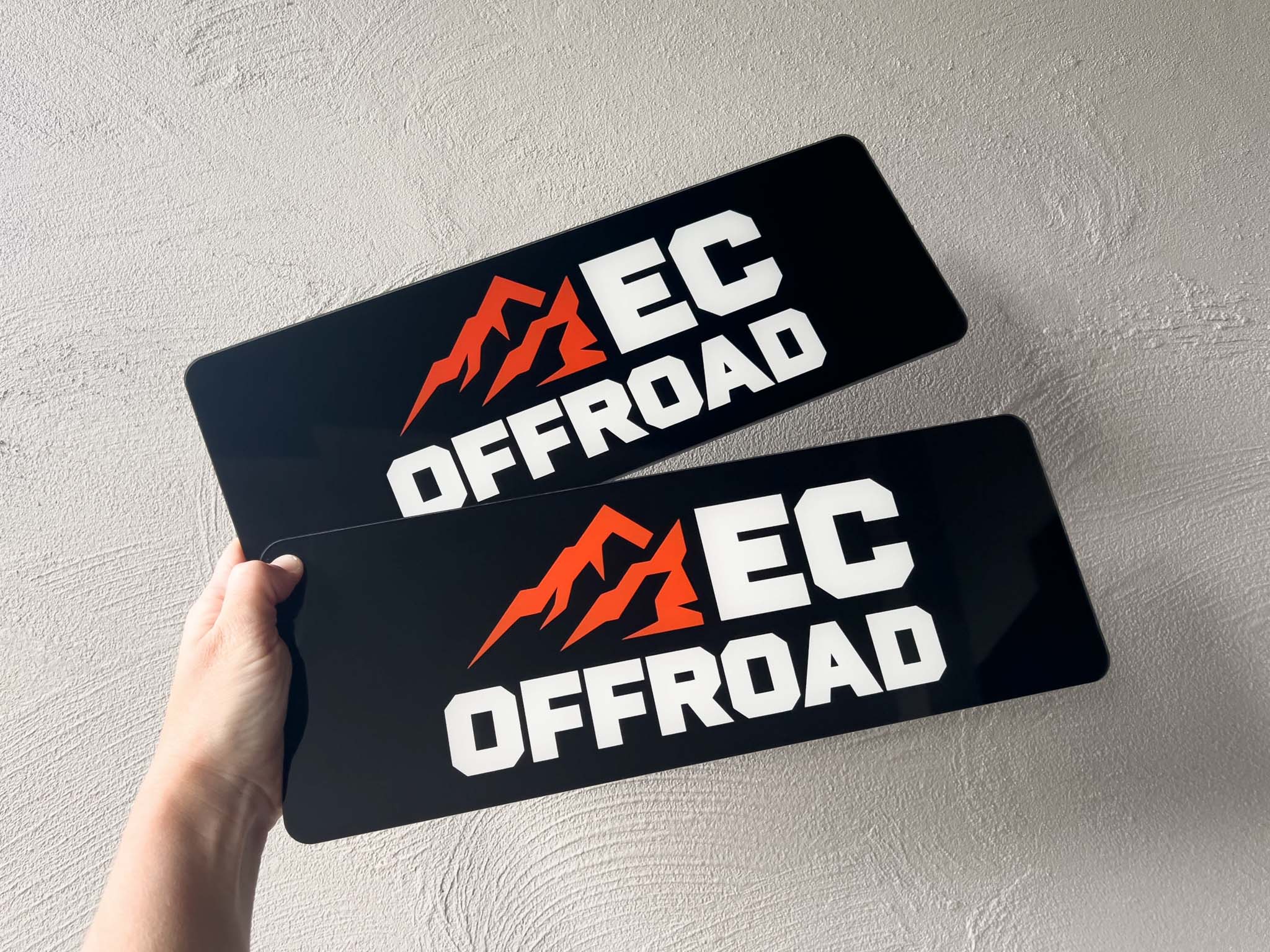 Two 'EC Offroad' custom acrylic cover plates held against a light grey background