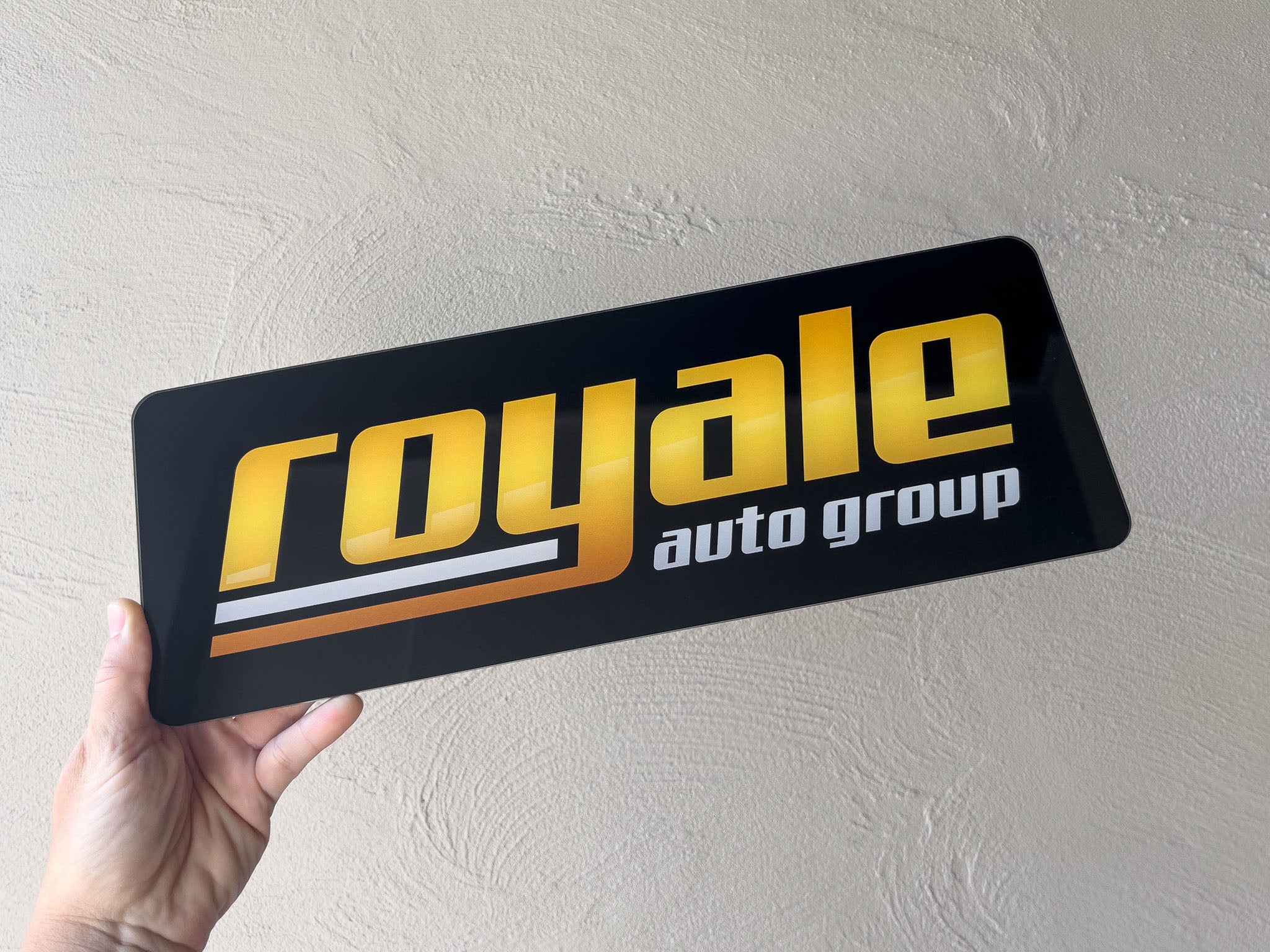A high gloss acrylic logo plate with the brand name 'Royal Auto Group'.