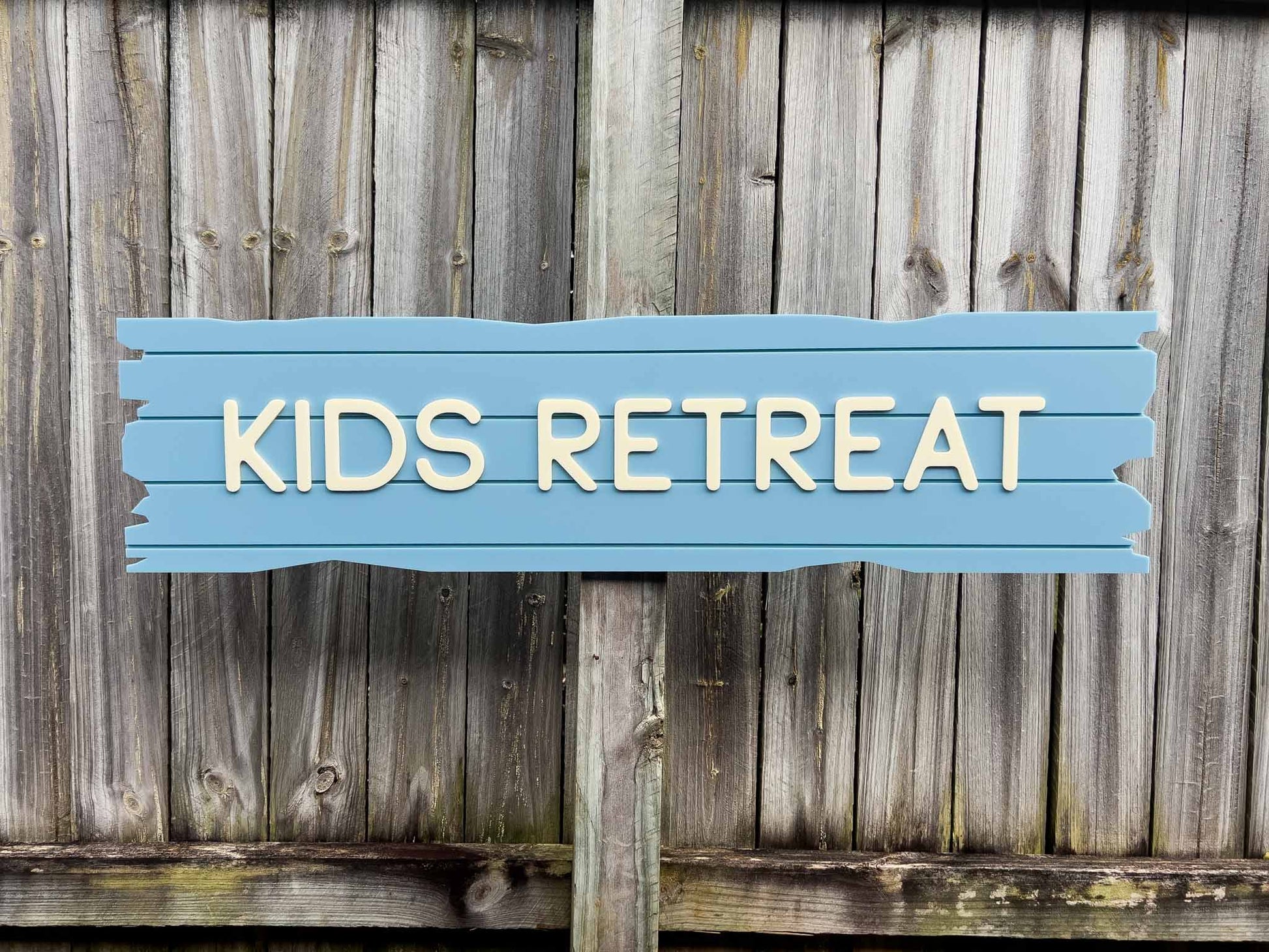 A coastal sea blue and cream driftwood sea wreckage style sign that says 'KIDS RETREAT'.
