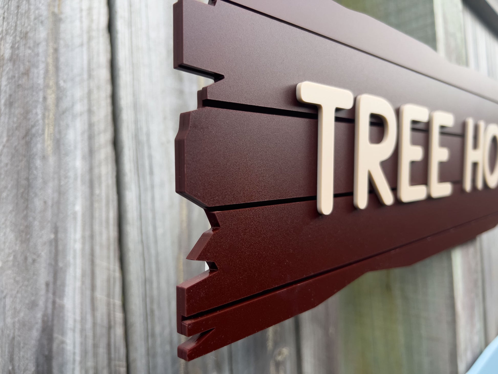 Close up side view of the Castaway plank sign in chocolate brown and beige lettering.