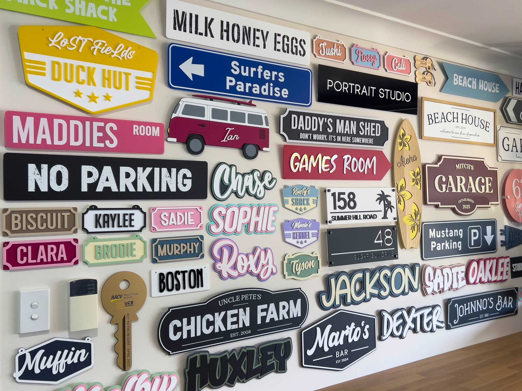 Collection of custom signs on a display wall at the Coji Designs studio workshop.