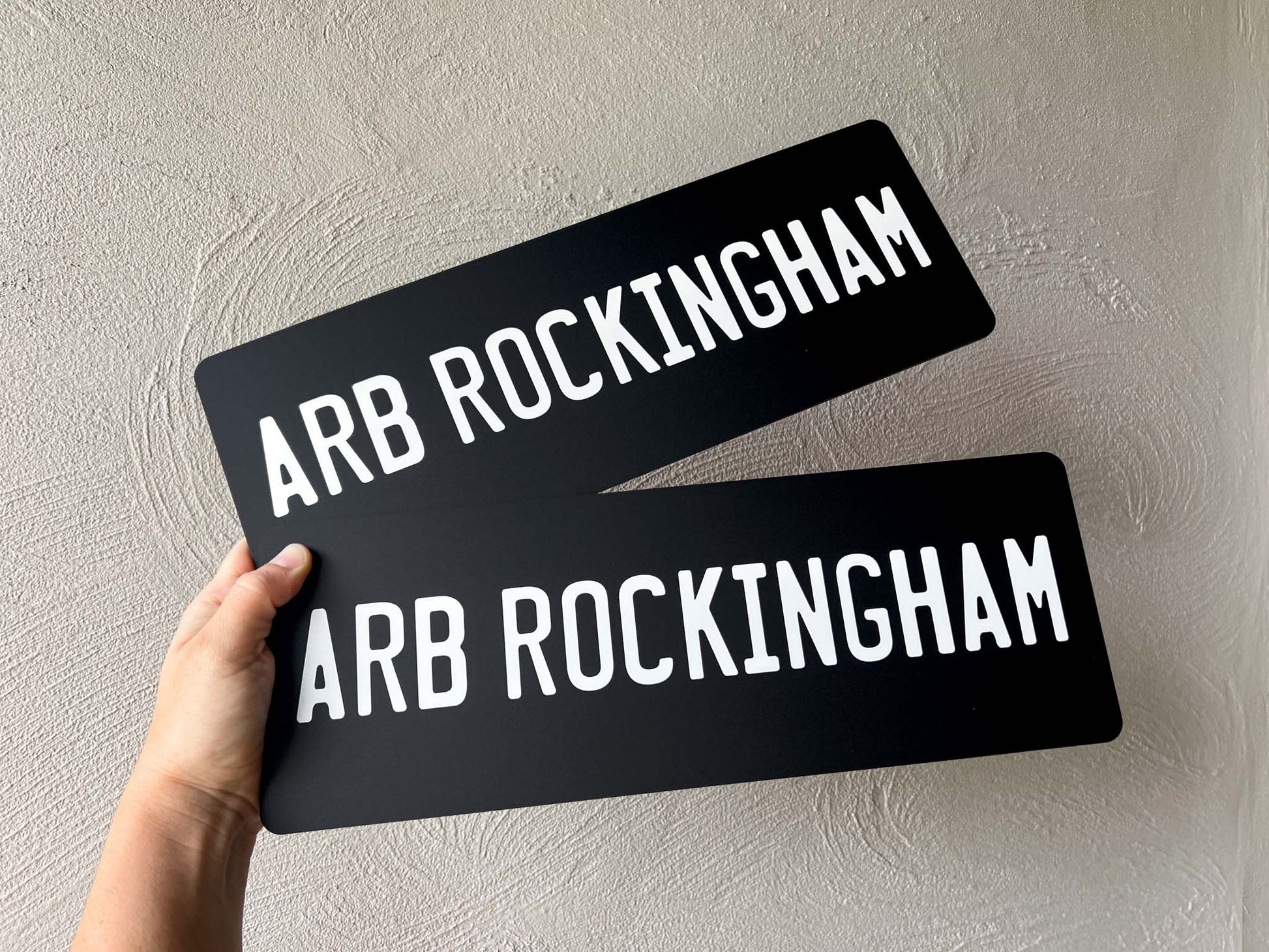 Two custom printed matte black acrylic number plate style signs that say 'ARB ROCKINGHAM' in white text.