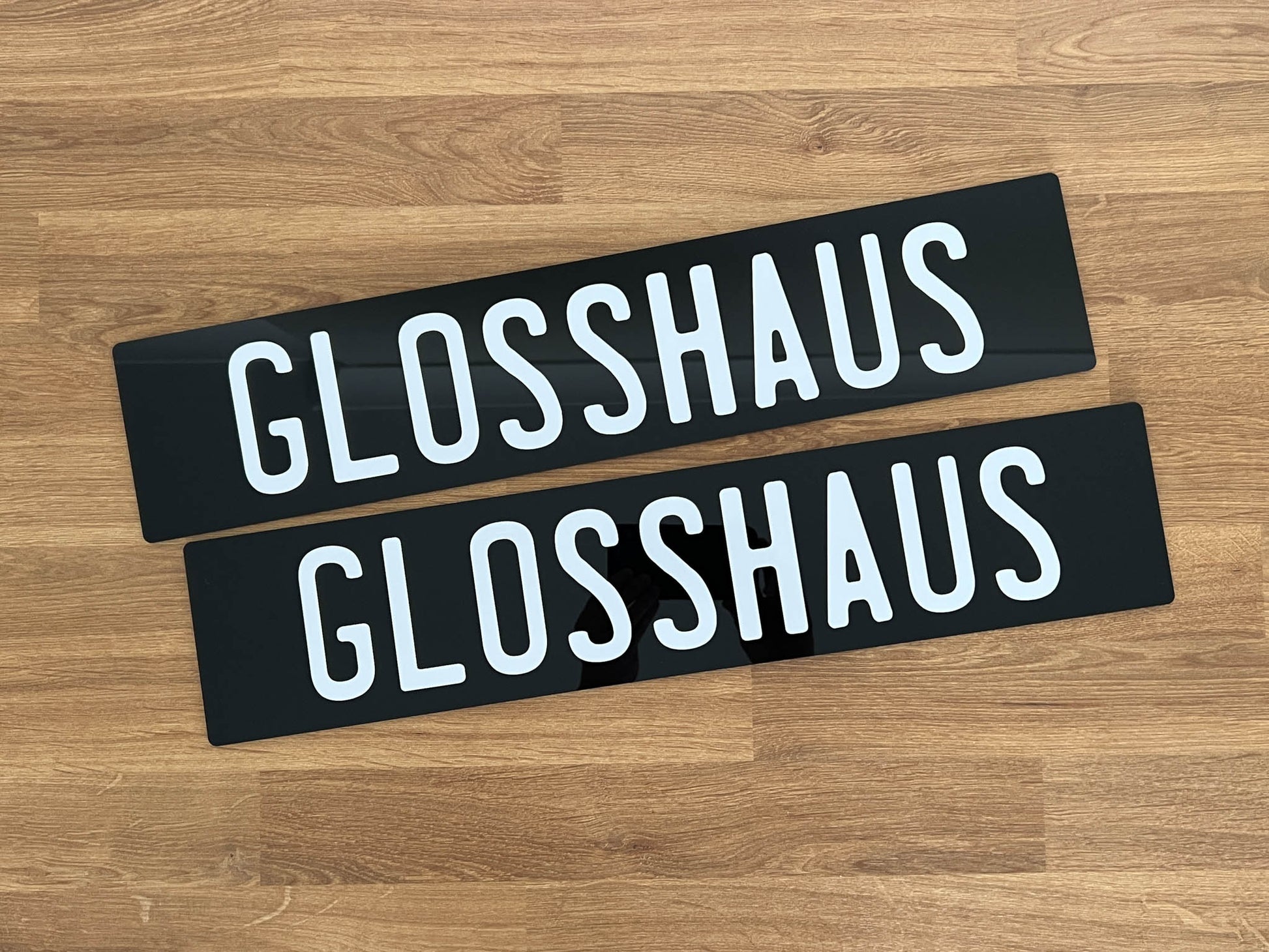 Two Euro style acrylic plates with the text 'GLOSSHAUS' print in white text.