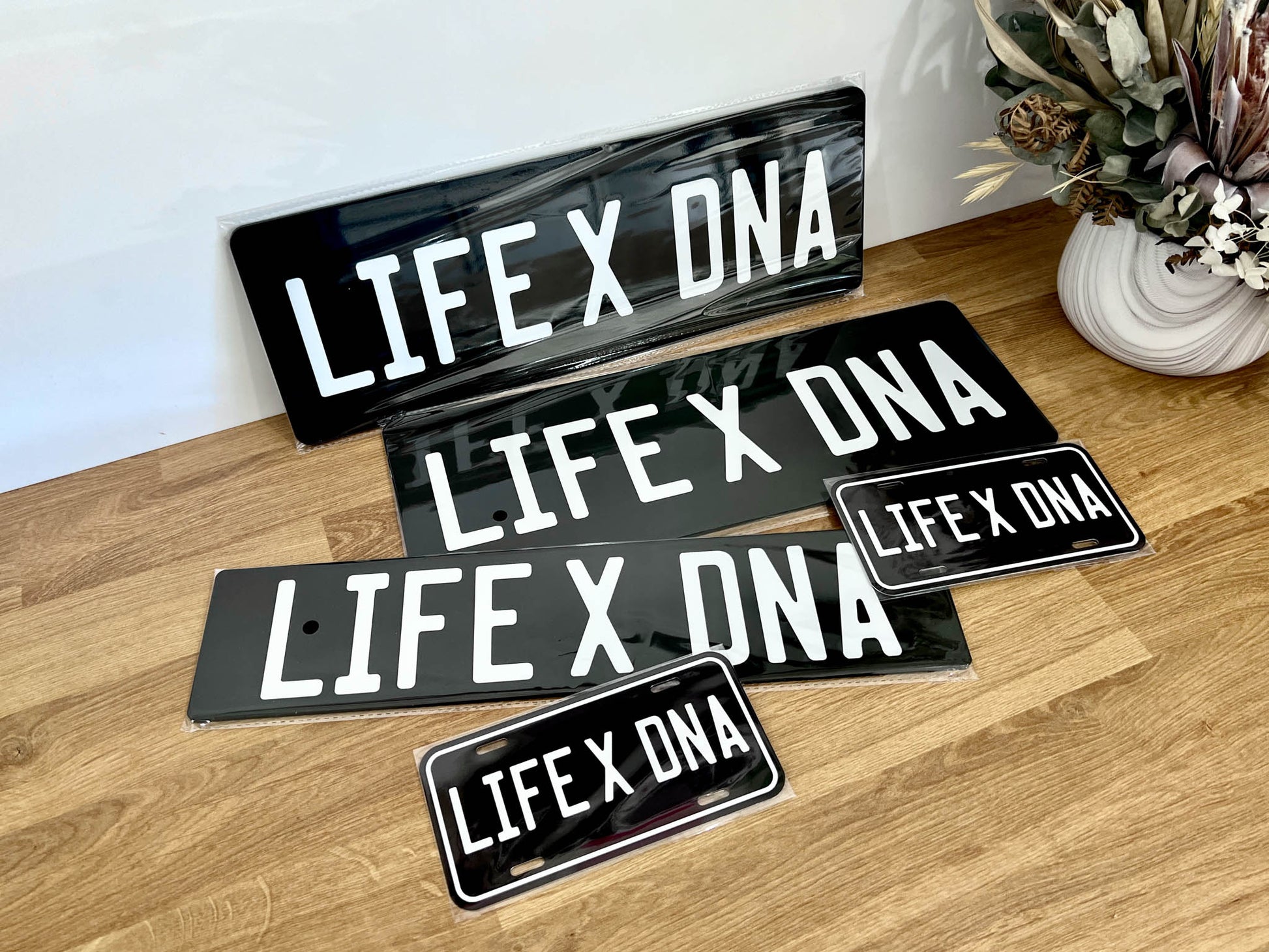 Set of glossy black plates in various sizes with 'LIFE X DNA' printed in white text sitting on a bench