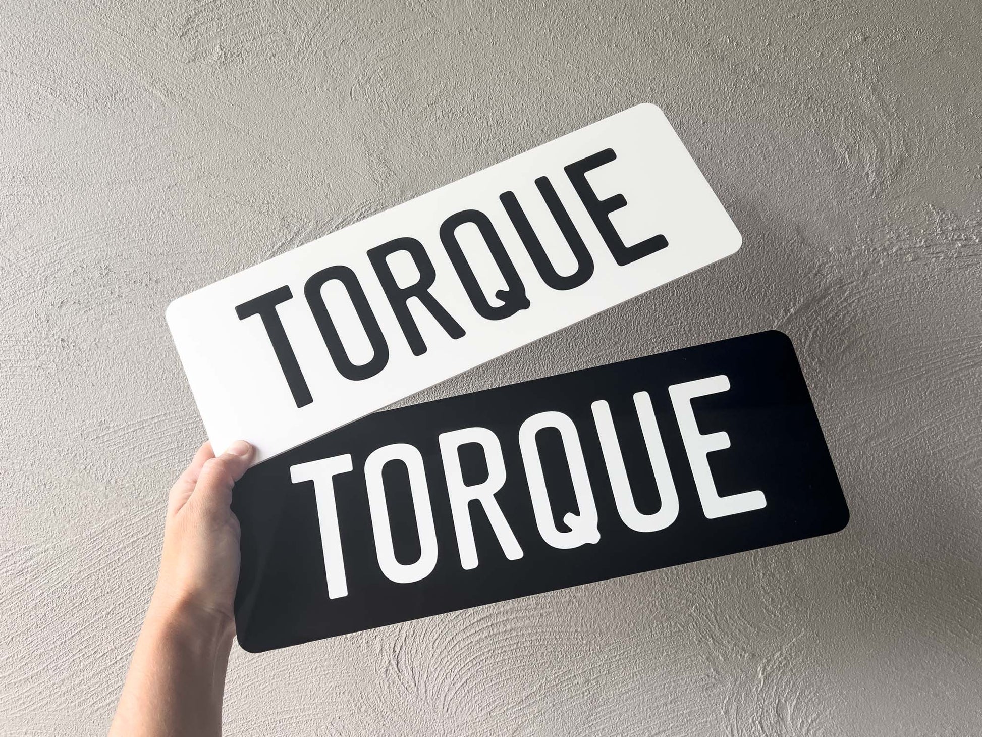 Two 'TORQUE' signs, one white and one black, held against a grey background.