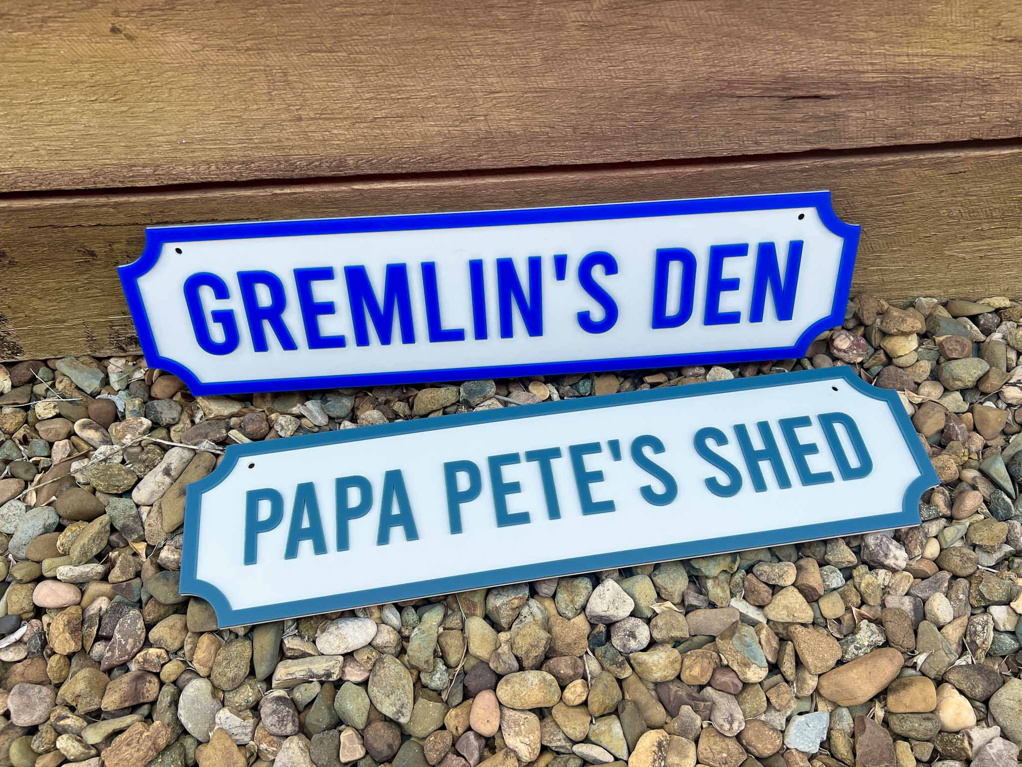 Two decorative signs with text on a gravel surface