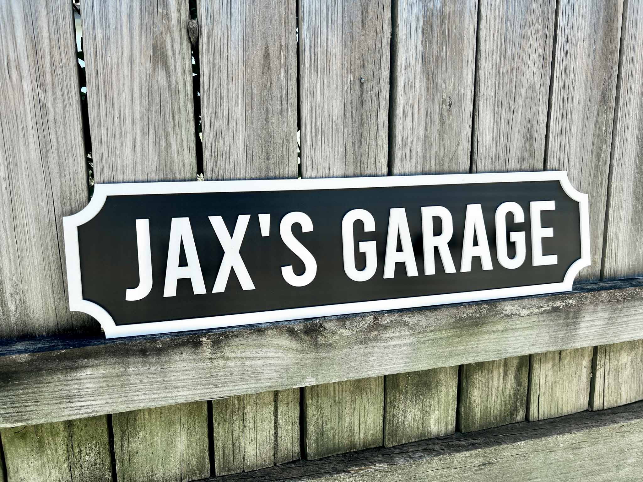 Sign with 'JAX'S GARAGE' text on a wooden background