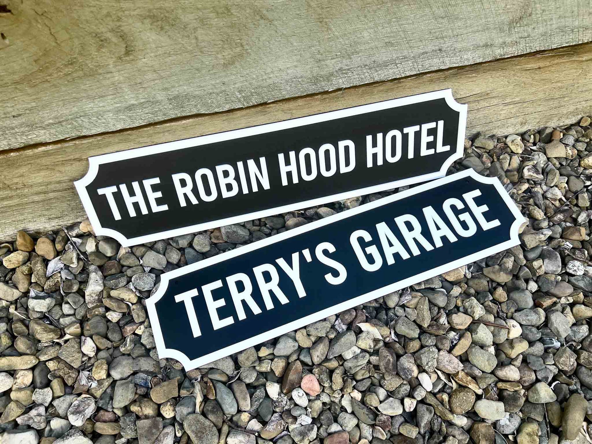 Two decorative signs reading 'The Robin Hood Hotel' and 'Terry's Garage' on a pebbled surface.