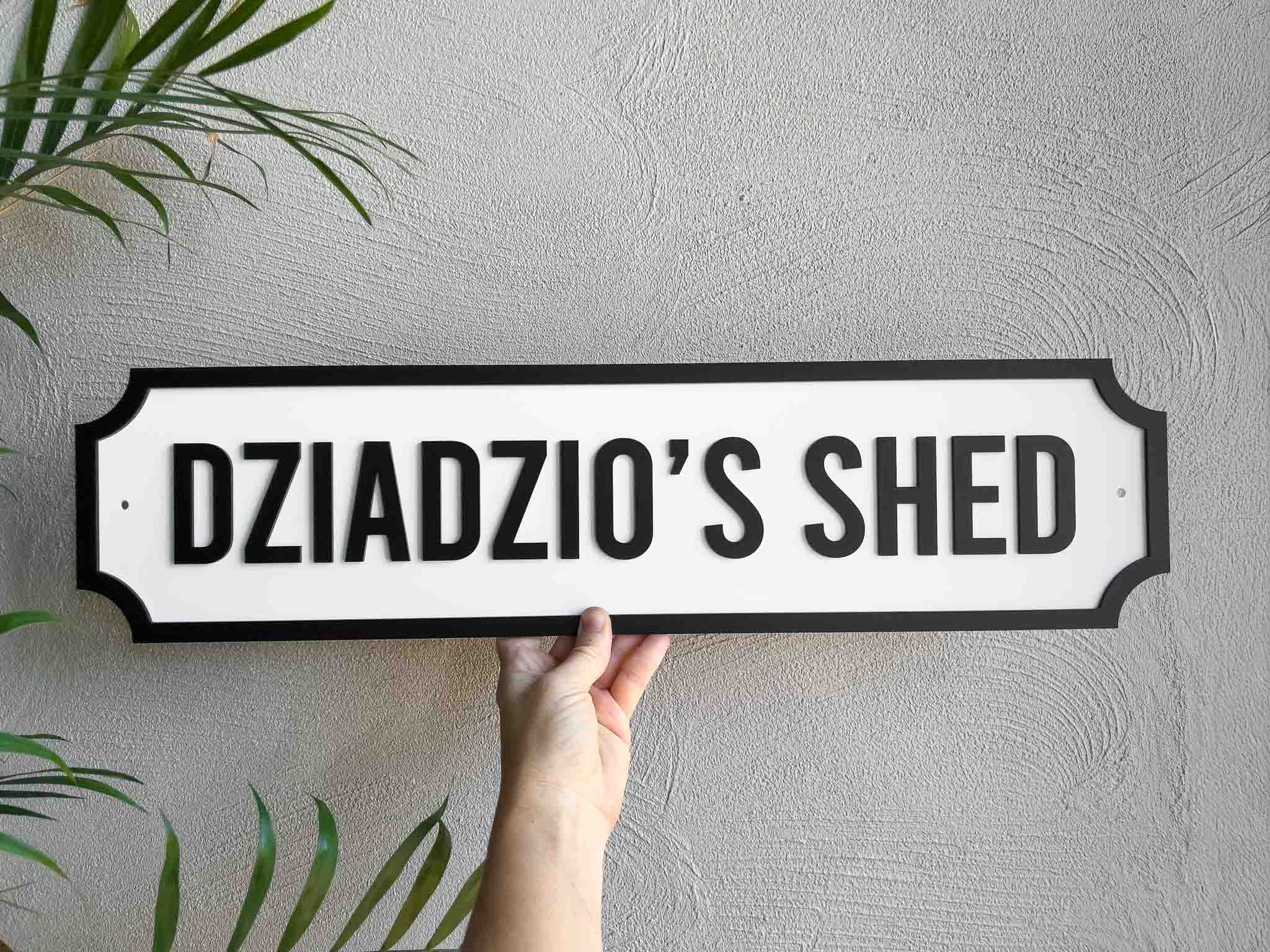Classic vintage panel style custom text sign that reads 'DZIADZIO'S SHED' in white and black.
