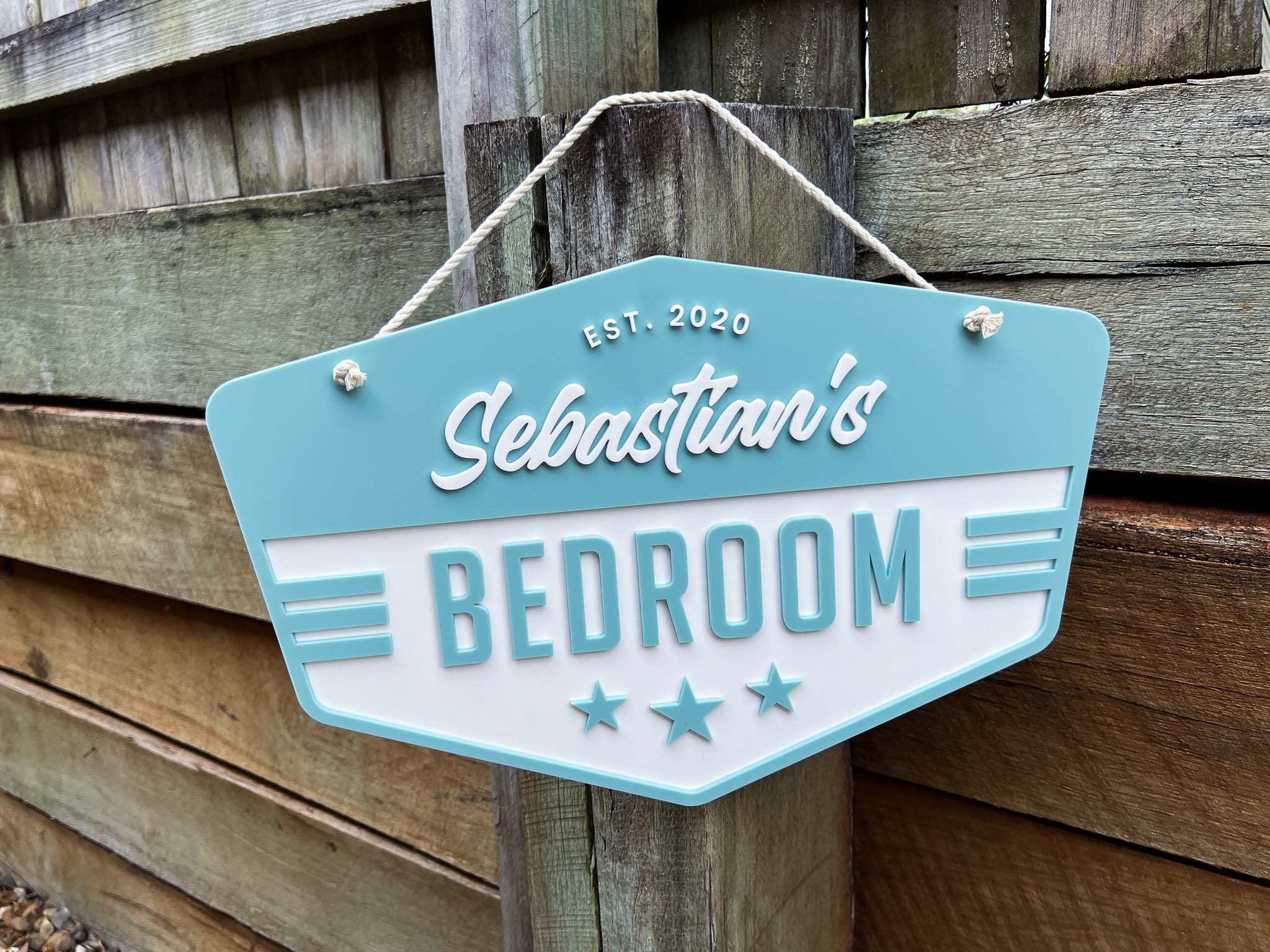 Classic vintage badge style personalised name plaque in a dusty coastal blue colour that says 'Sebastian's Bedroom'.