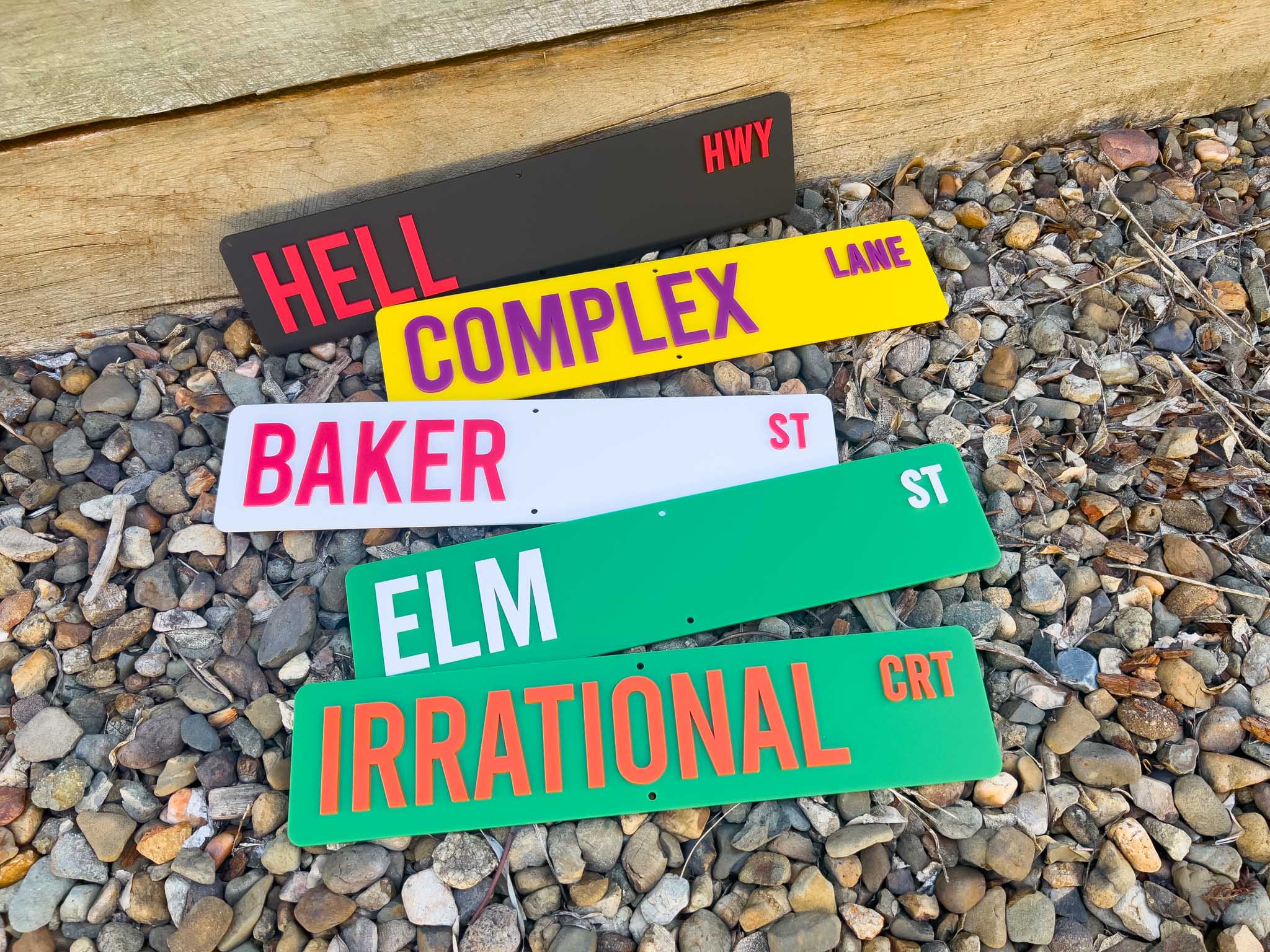 Colorful street name signs on a gravel surface