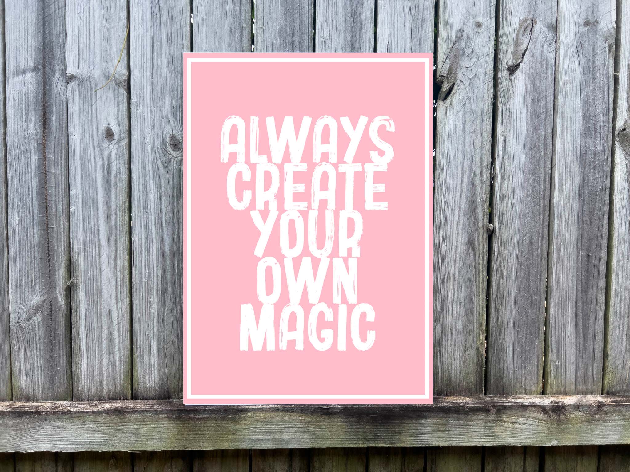 Pink UV printed sign with 'Always Create Your Own Magic' white text on a wooden background