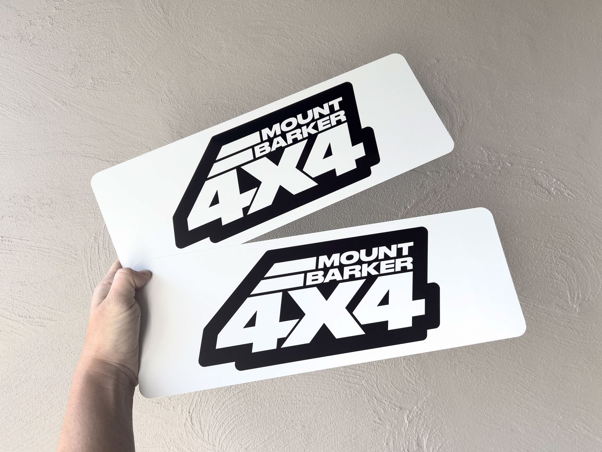 Two 'Mount Barker 4X4' metal plates held against a neutral background
