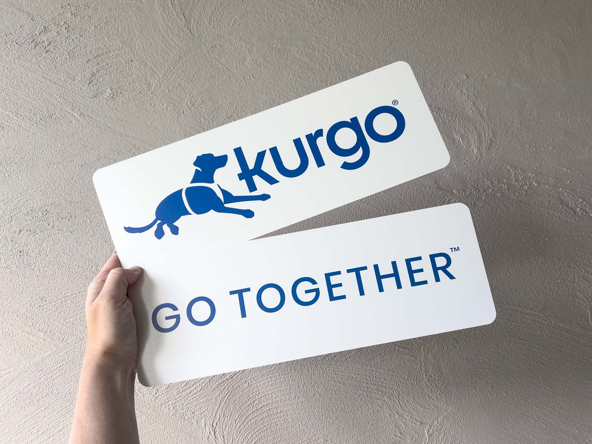 Two Kurgo branded aluminium signs held against a neutral background