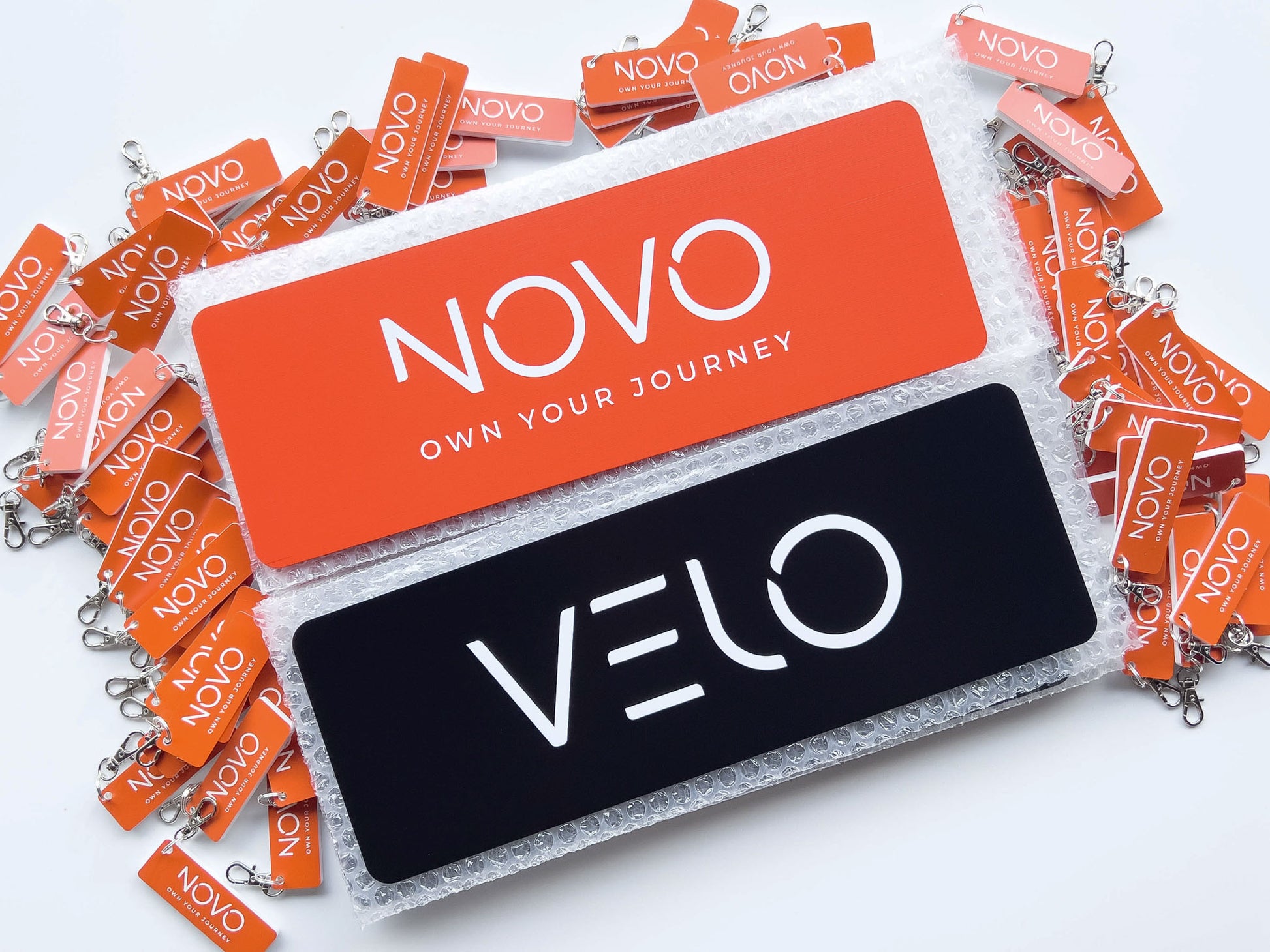 NOVO and Velo branded keychains and plates on a white background