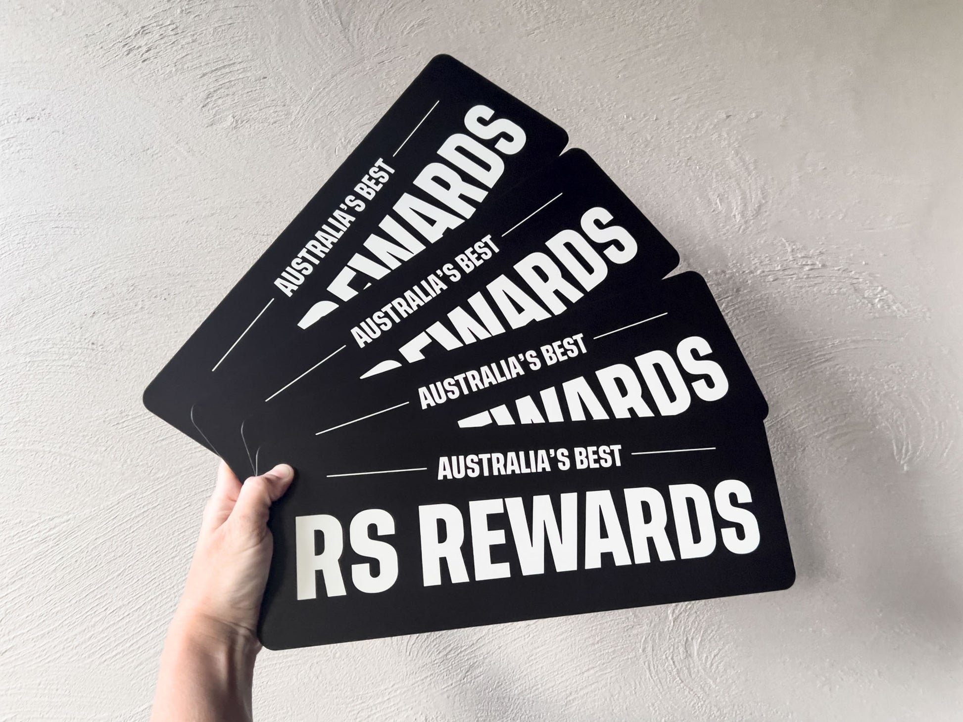 Four 'Australia's Best RS Rewards' custom printed logo plates held against a light grey background