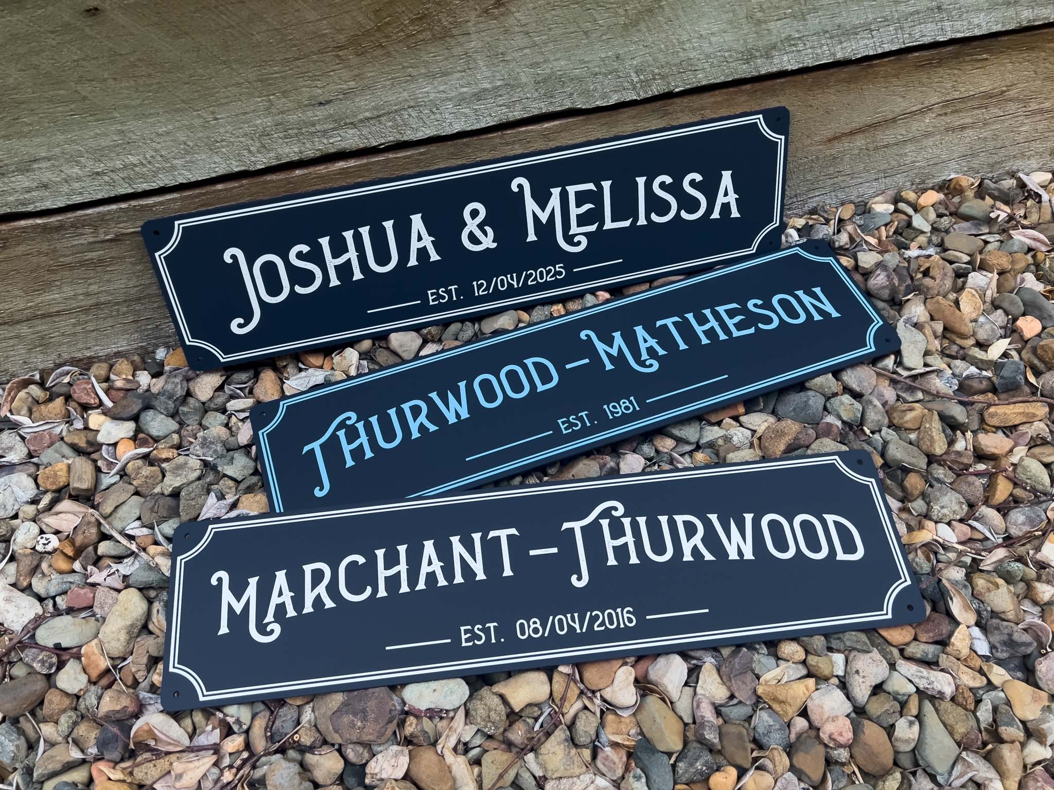 Three custom printed saloon style bar signs with names printed in a deep blue colour with white text.