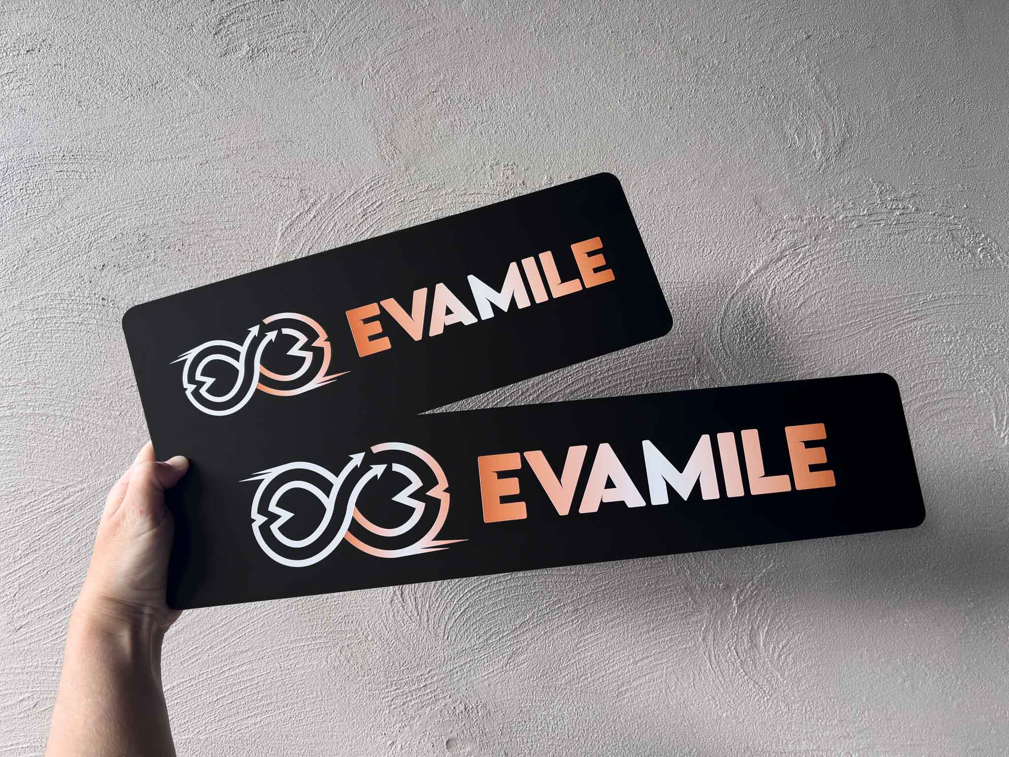 Two custom printed black acrylic logo plates with the brand 'EVAMILE' UV printed with a matte finish.