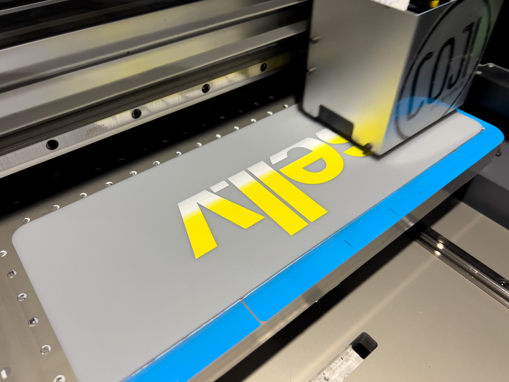 A custom Lancaster logo plate being printed onto a matte grey plate