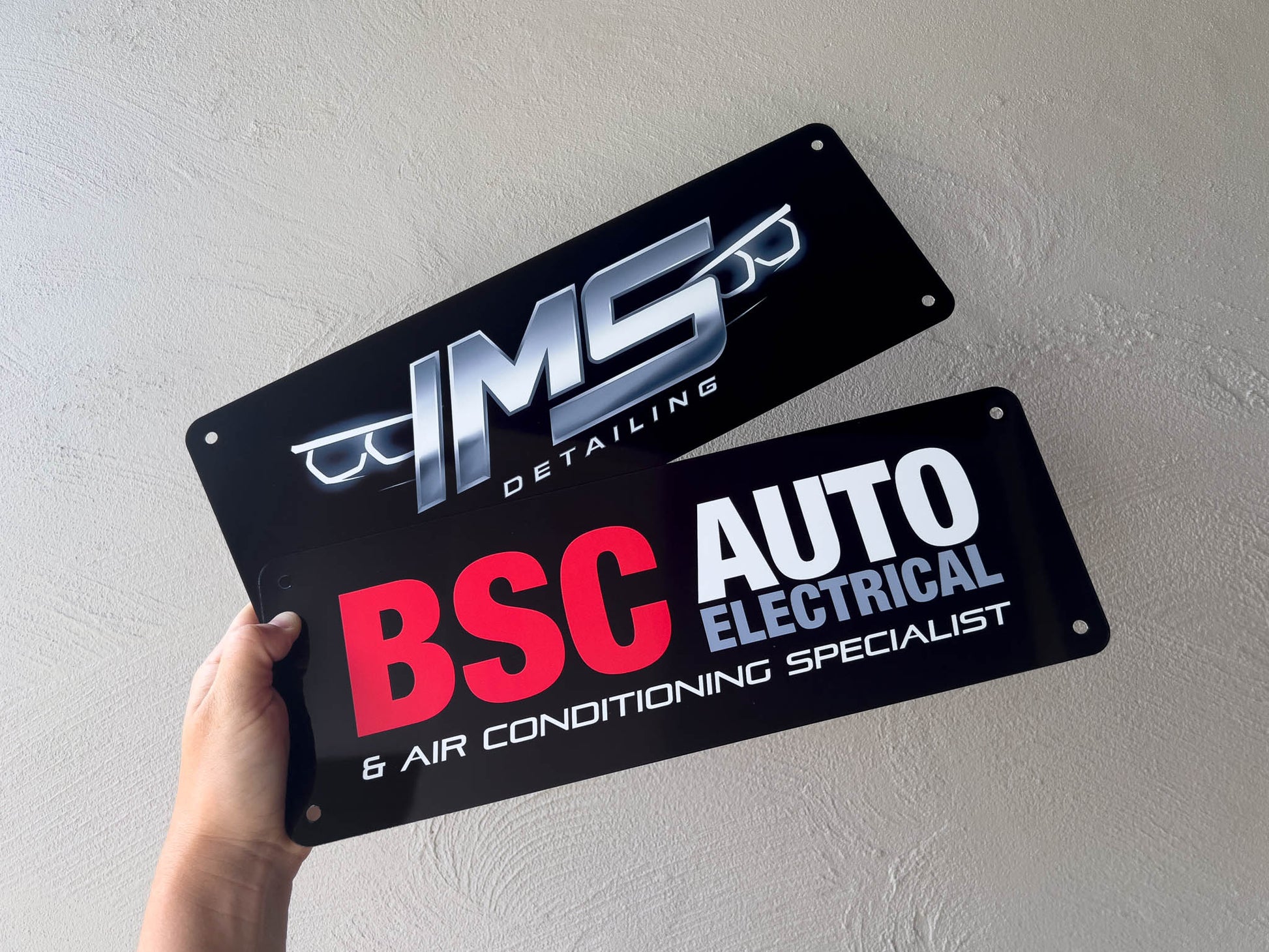 Two automotive-themed license plate designs held against a light gray background.