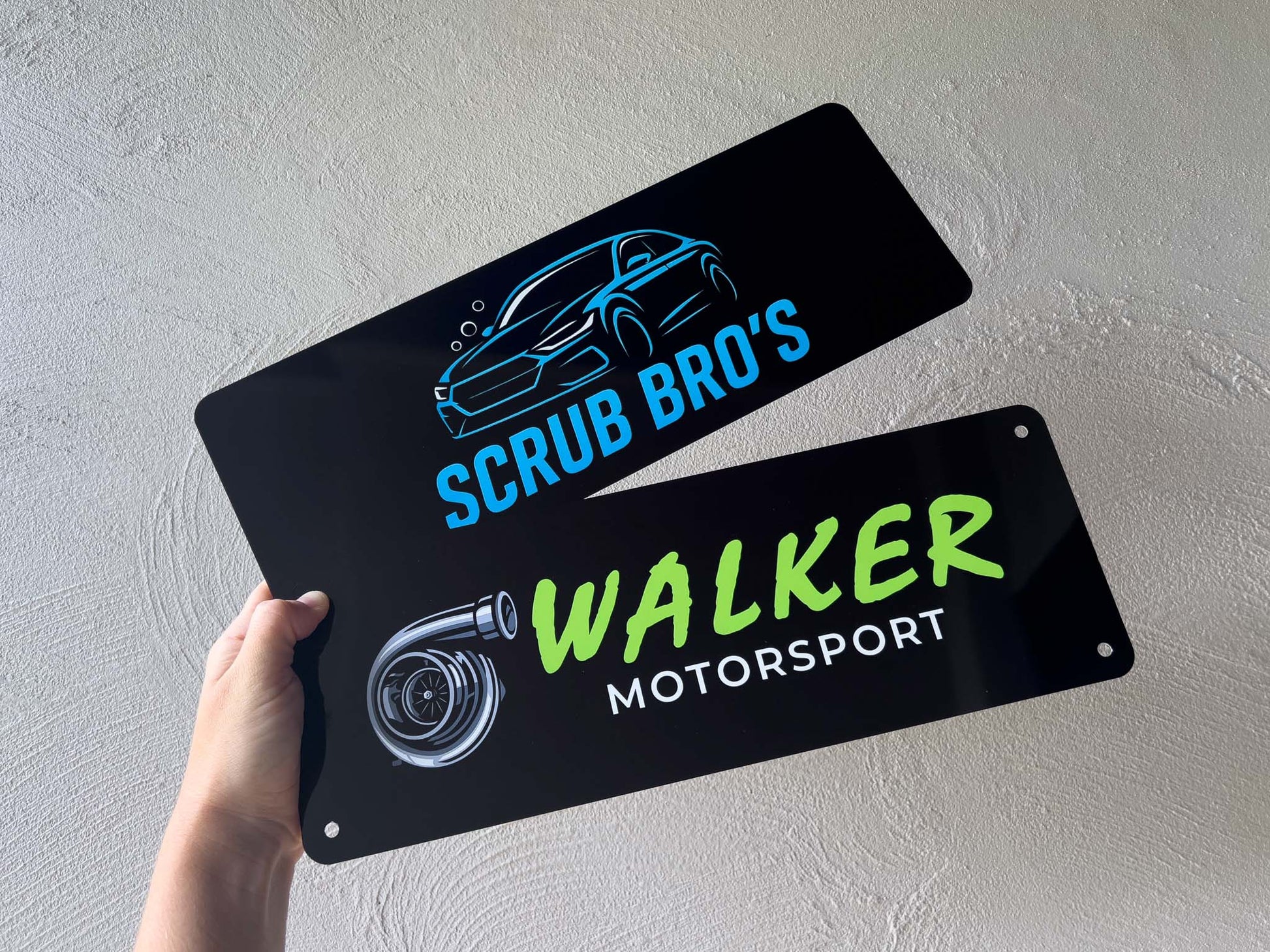 Two black logo plates with car-related graphics for business promotion