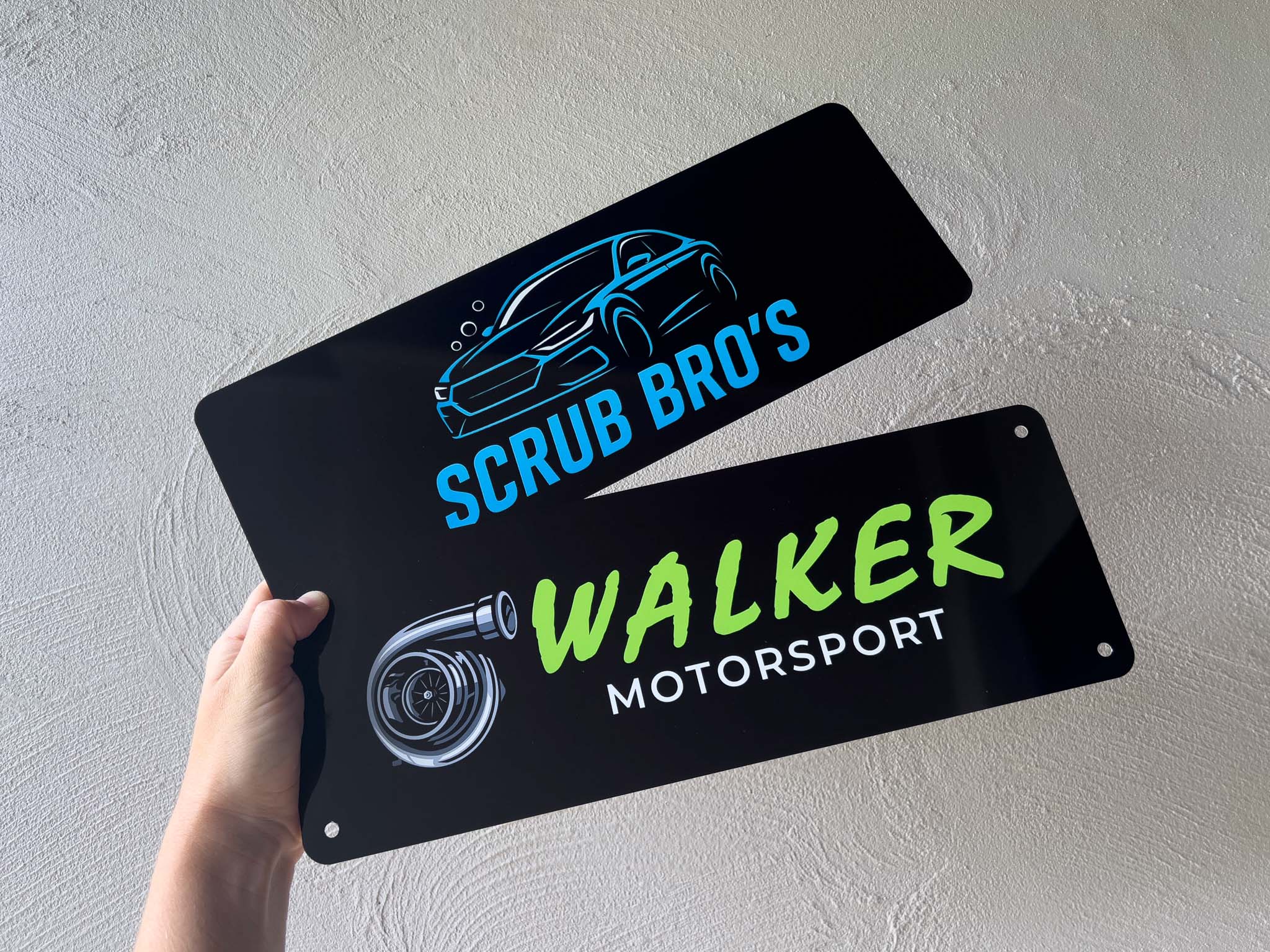 Two black logo plates with car-related graphics for business promotion
