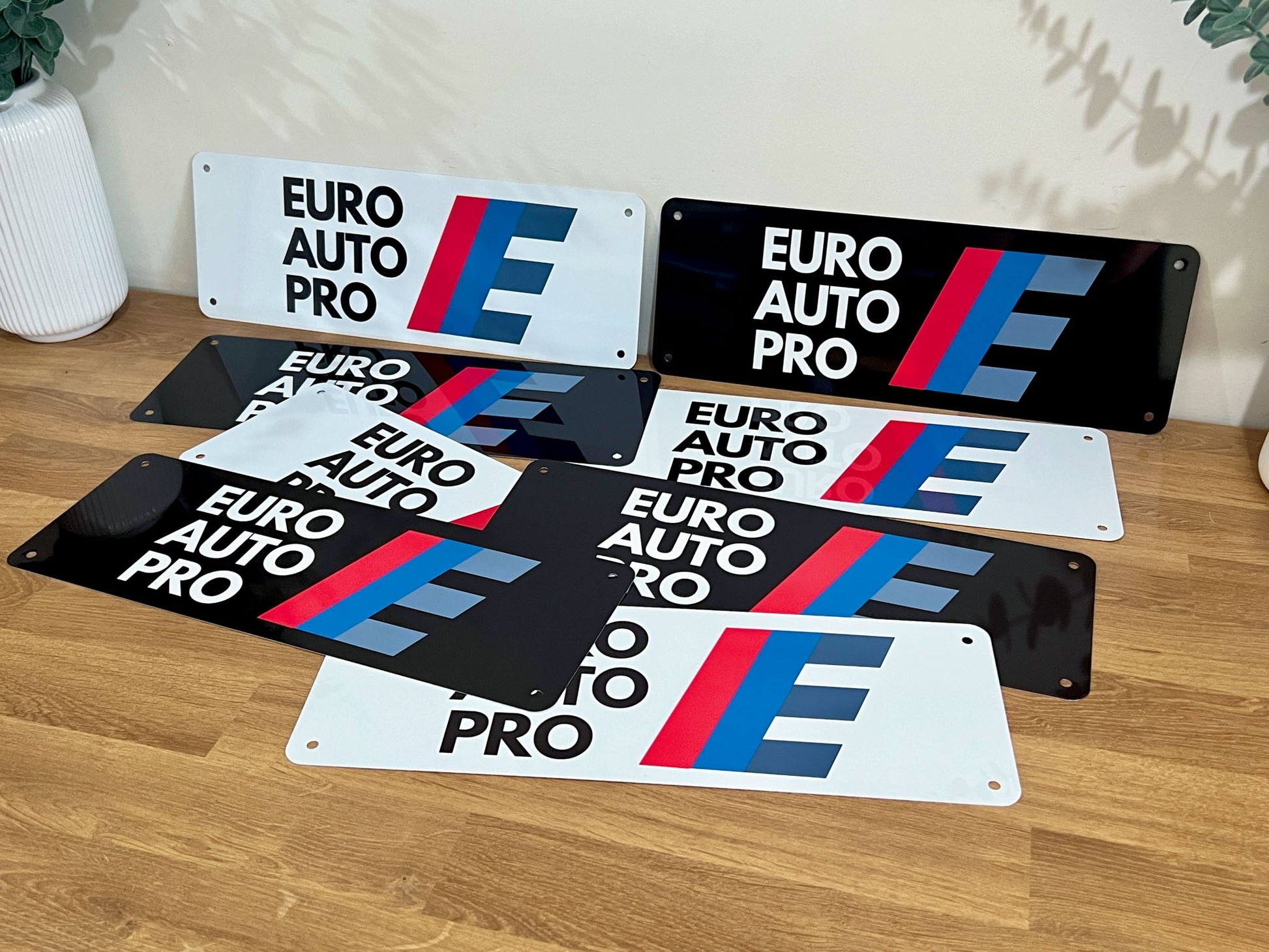 Collection of 'EURO AUTO PRO' branded logo plates on a wooden table