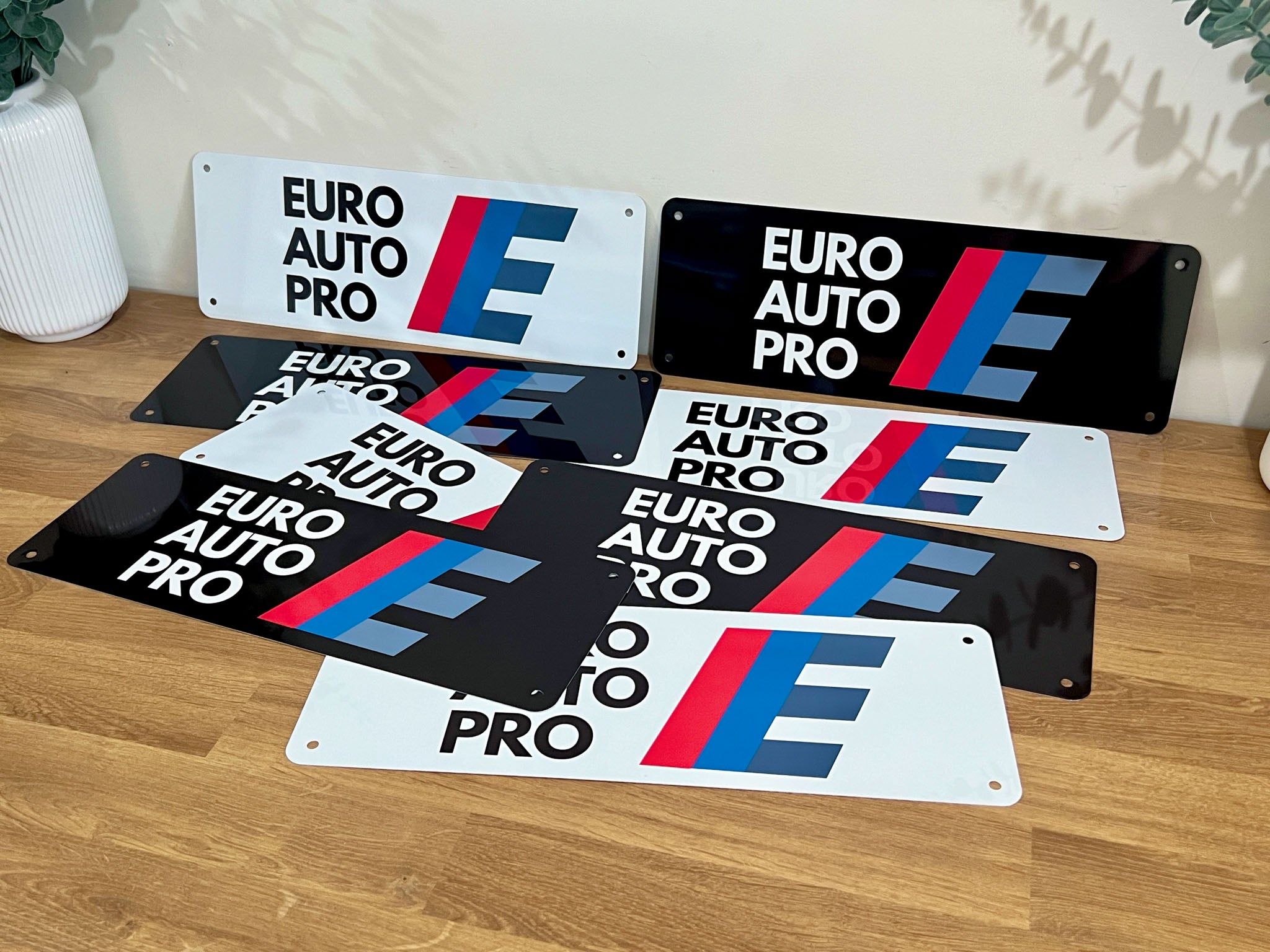 Collection of 'EURO AUTO PRO' branded logo plates on a wooden table