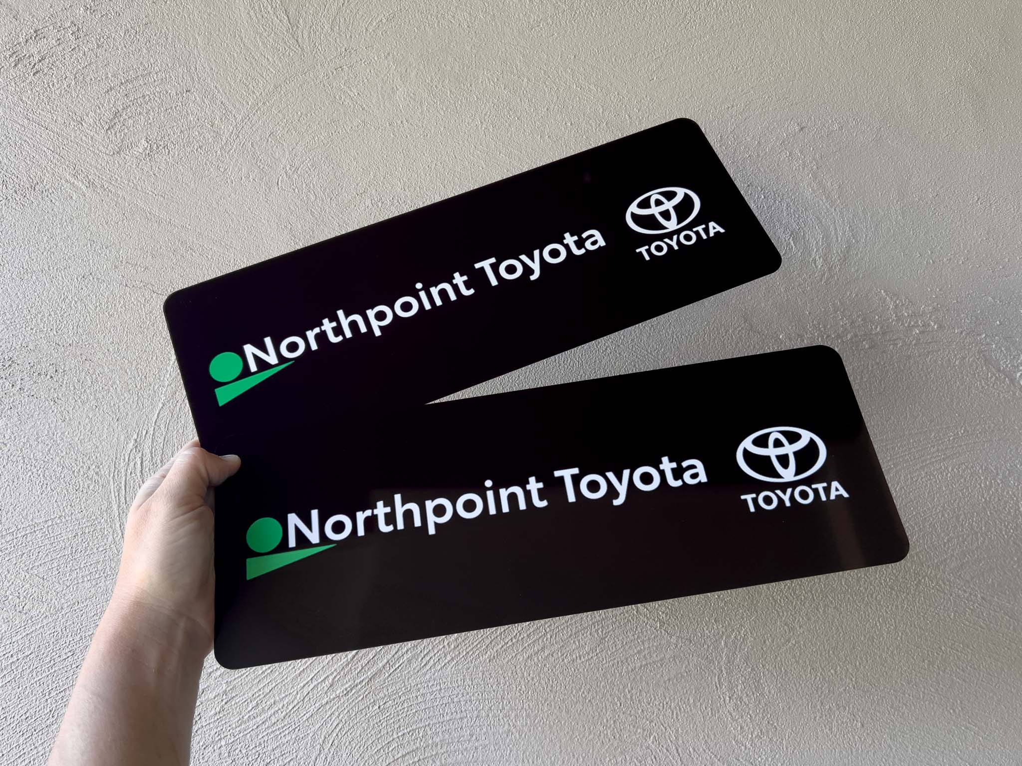 Two black Northpoint Toyota logo plates held against a light background
