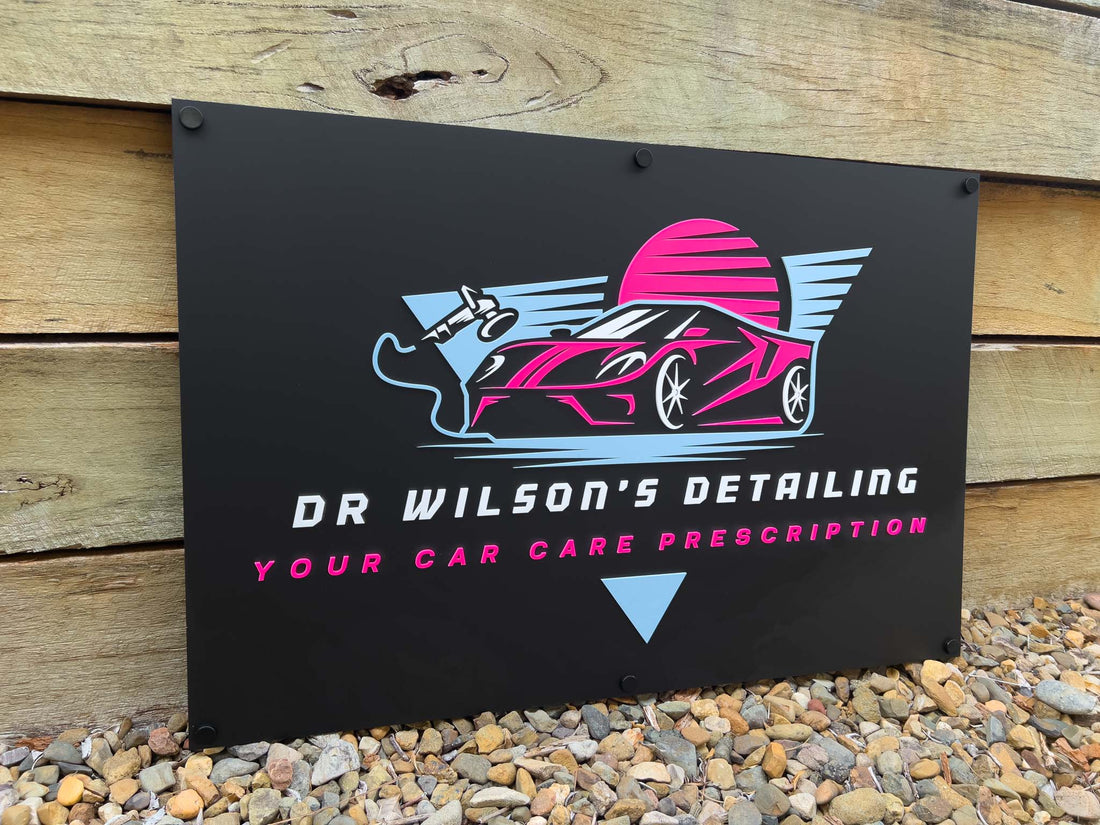 A large 3D acrylic logo plaque for 'Dr Wilson's Detailing' in black, blue and pink.