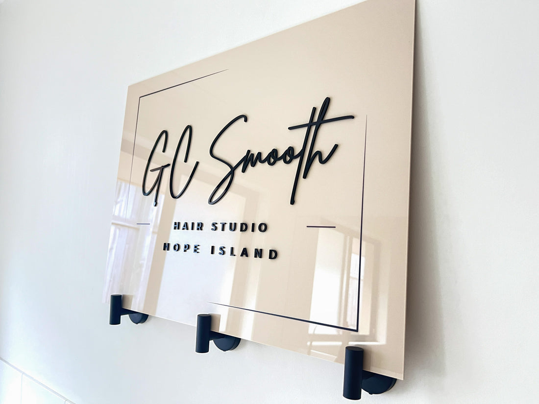 Beige sign with 'GC Smooth Hair Studio Hope Island' on a white wall