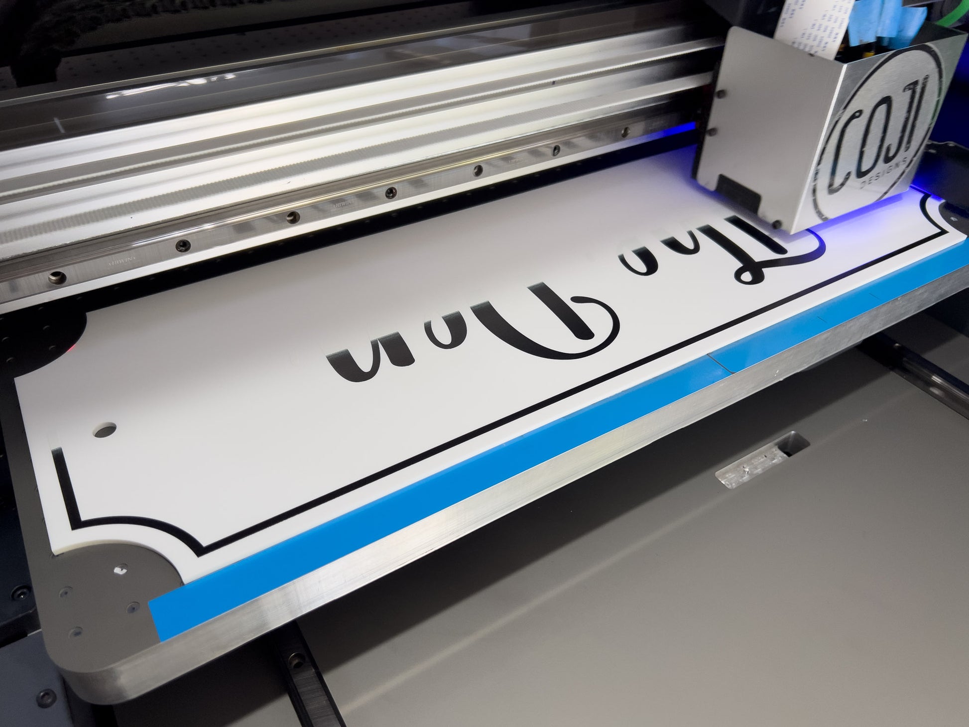 A custom white and black Maison sign being printed