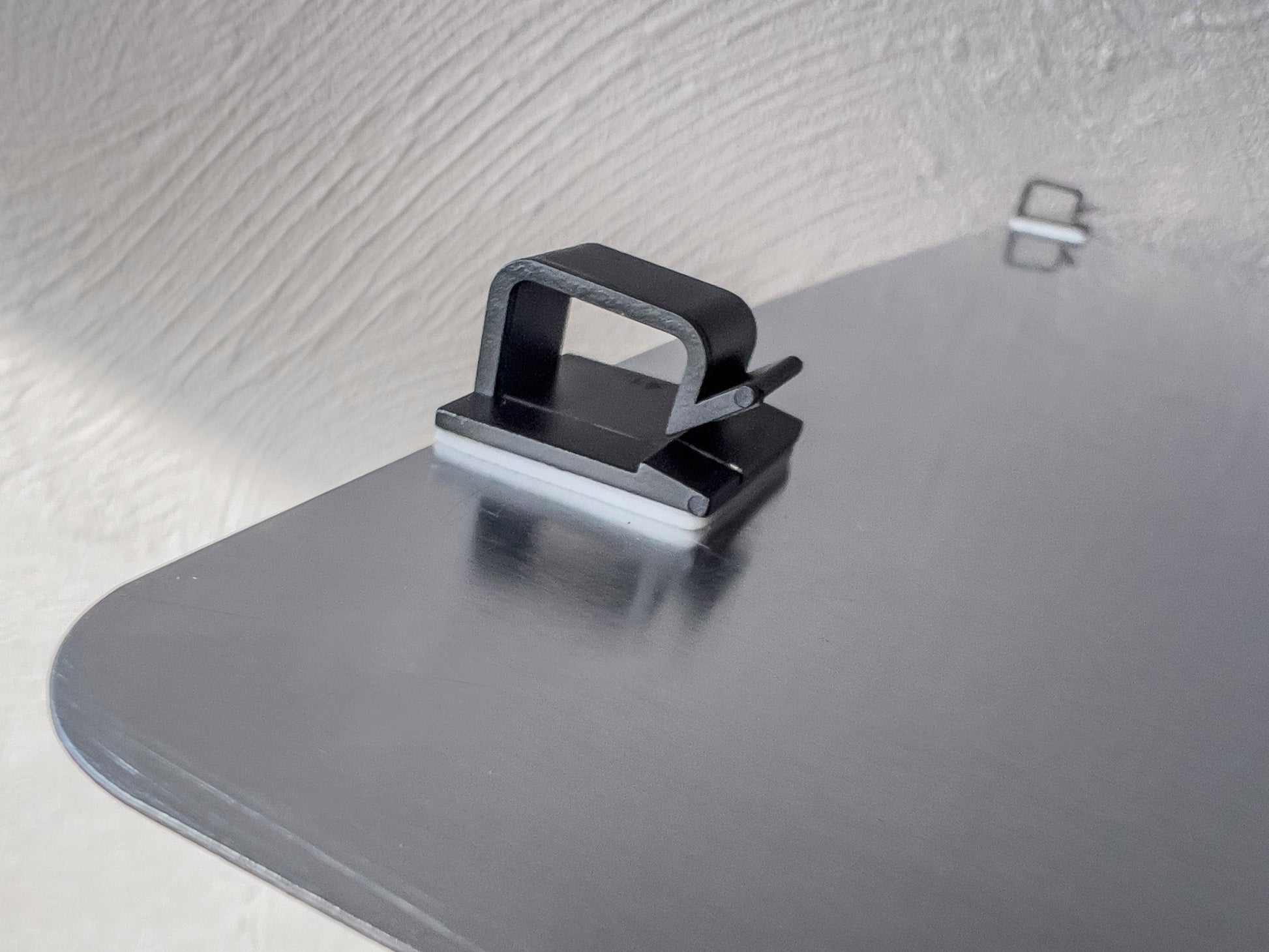 Plastic mounting clip on the back of an aluminium logo cover plate