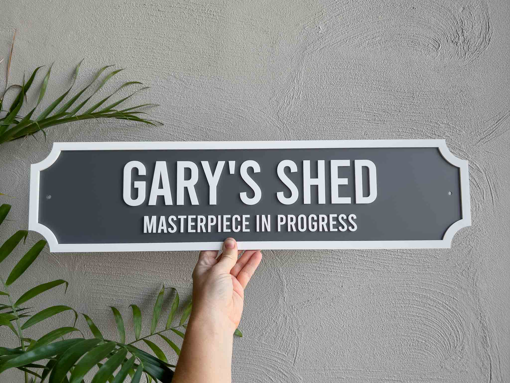 Custom classic signboard style 3D acrylic sign that reads 'GARY'S SHED' in grey and white.