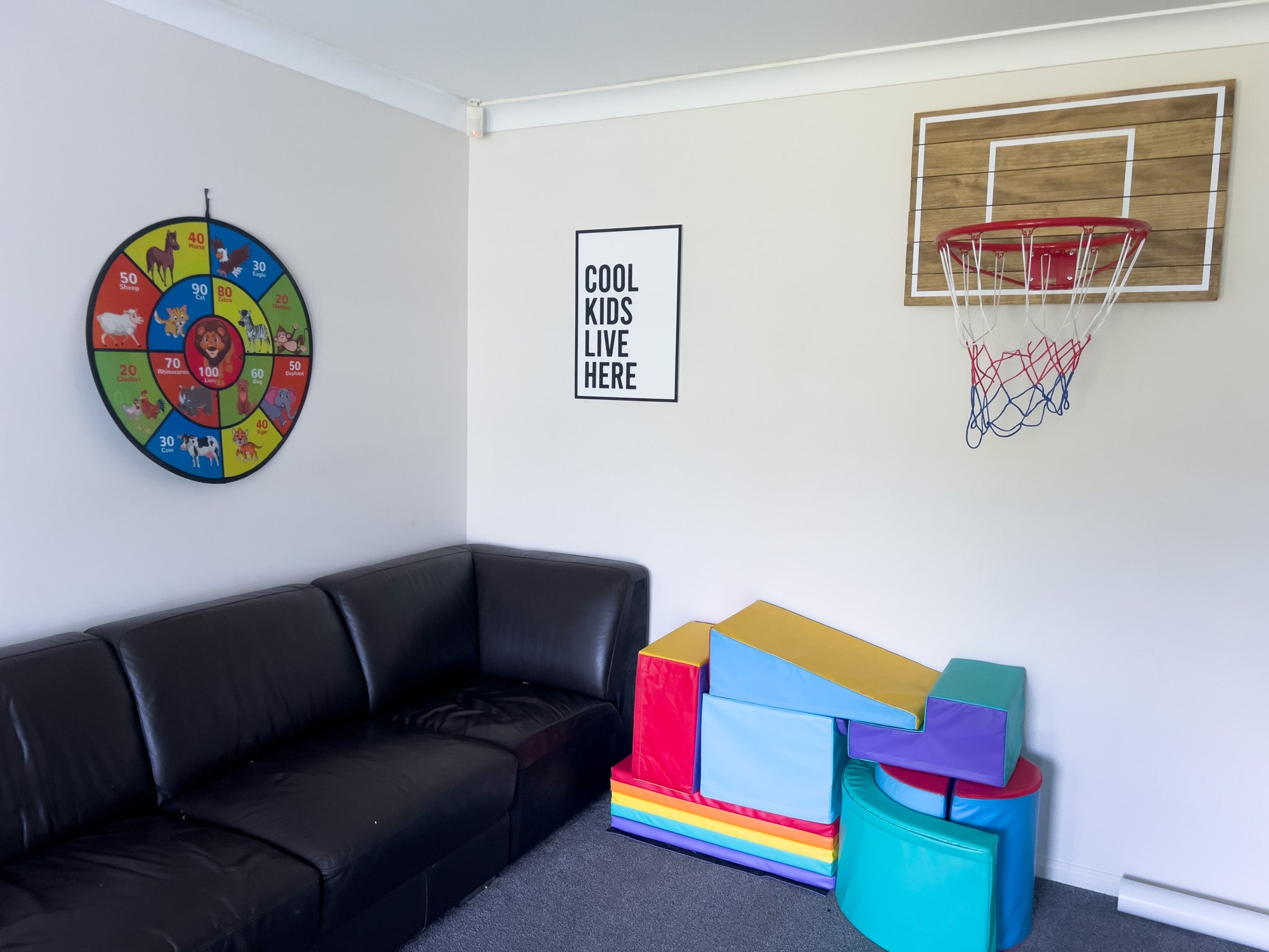 Custom black and white 3D quote sign hanging in a kids playroom. The sign says 'COOL KIDS LIVE HERE'.