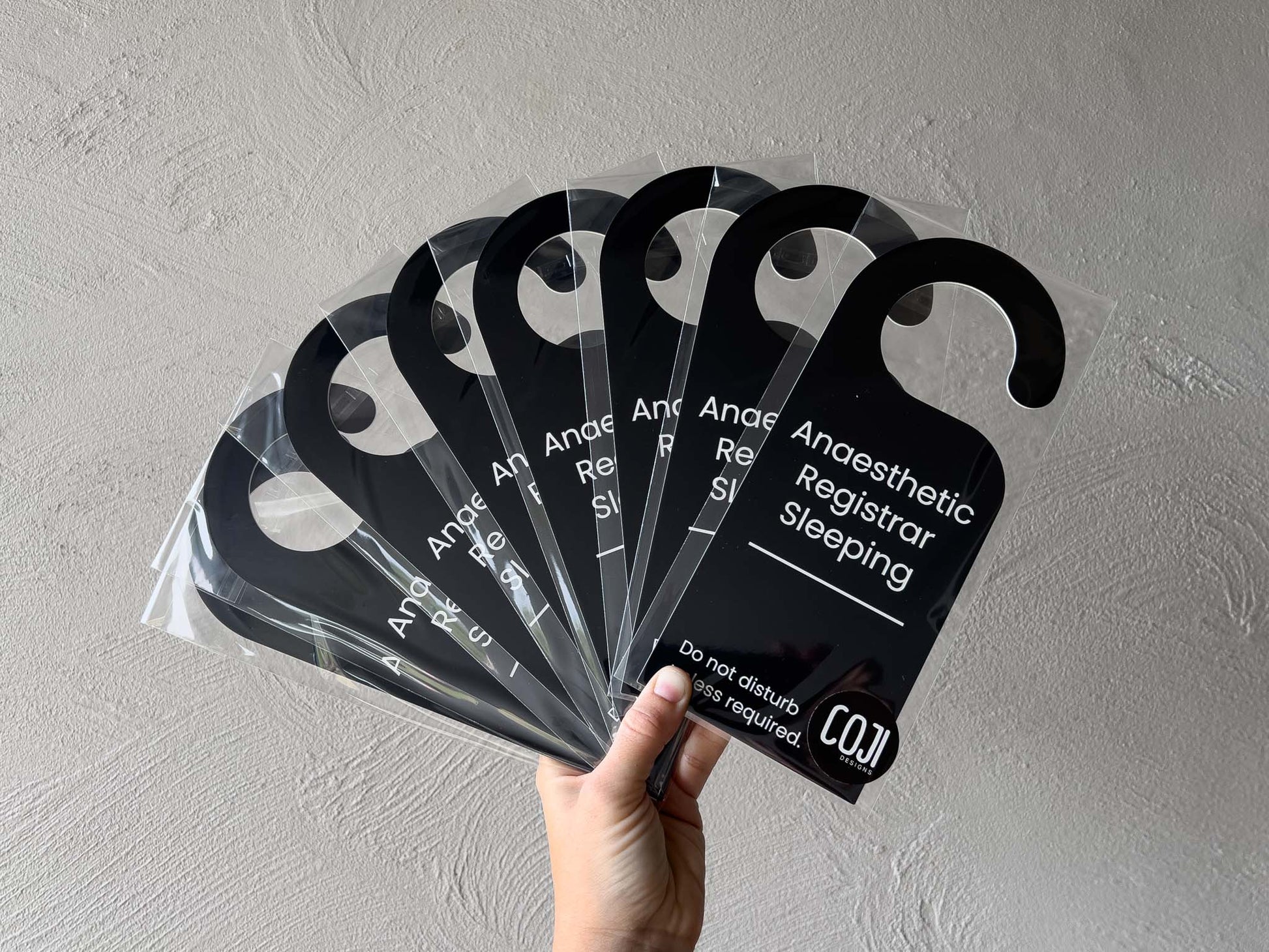 A collection of black door hangers with white text that say 'Anaesthetic Registrar Sleeping. Do not disturb unless required.'.