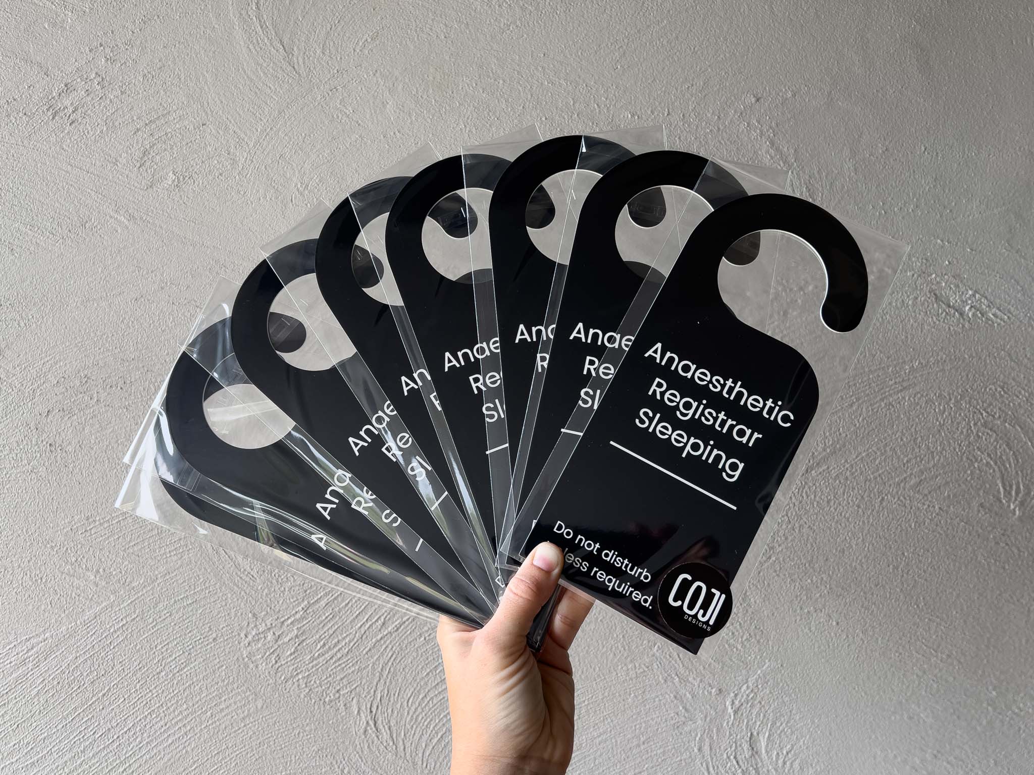 A collection of black door hangers with white text that say 'Anaesthetic Registrar Sleeping. Do not disturb unless required.'.