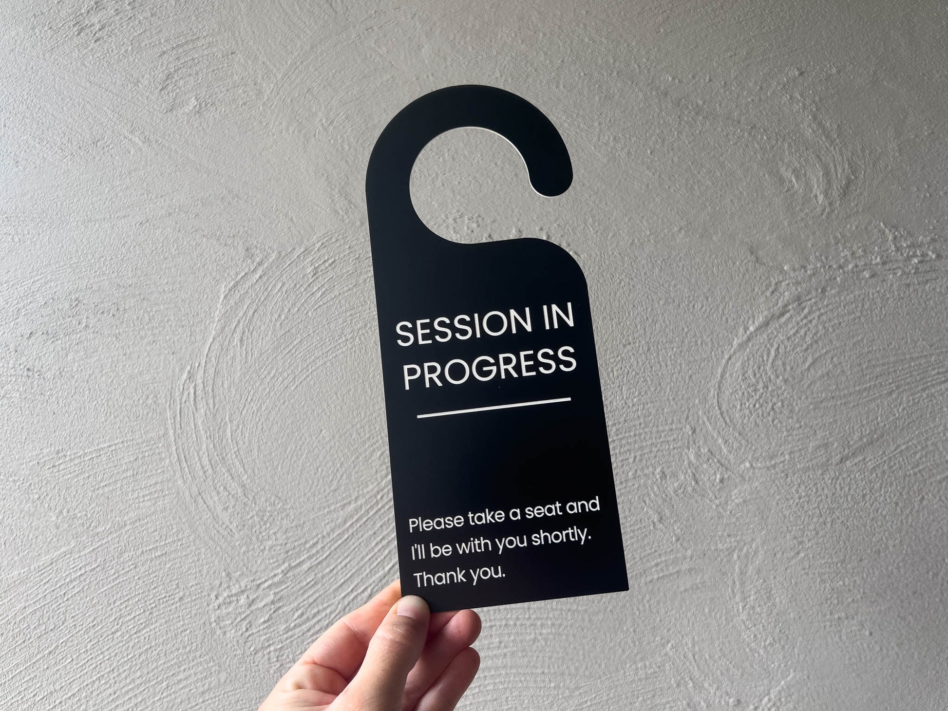 A professional black and white door hanger used in a botique studio to advise that a session is currently in progress.