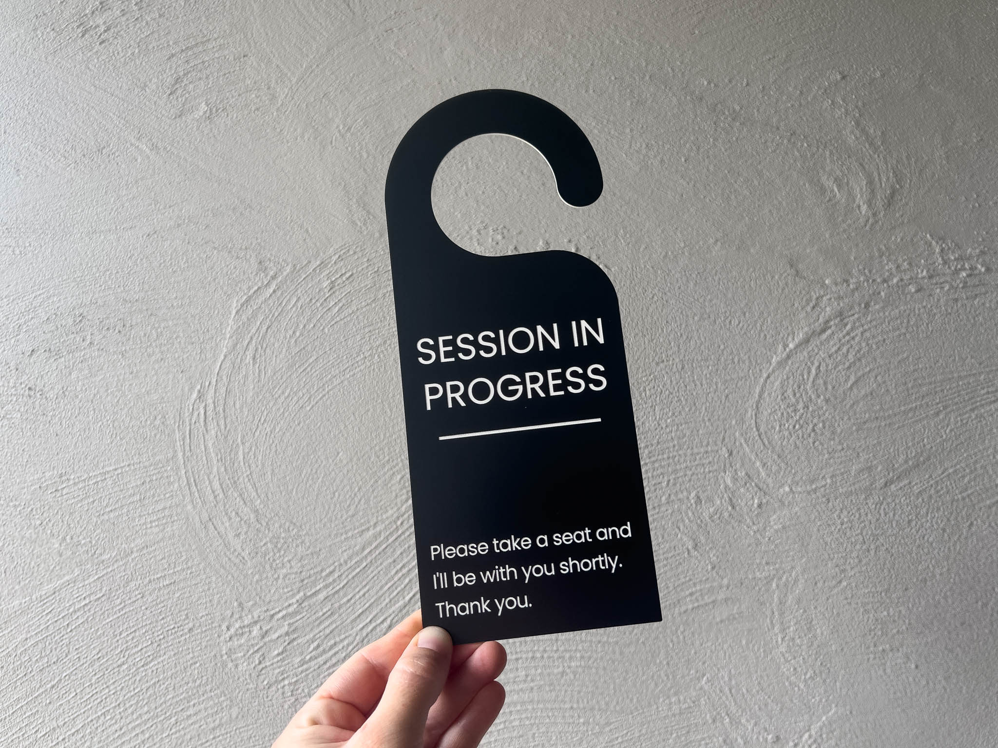A professional black and white door hanger used in a botique studio to advise that a session is currently in progress.