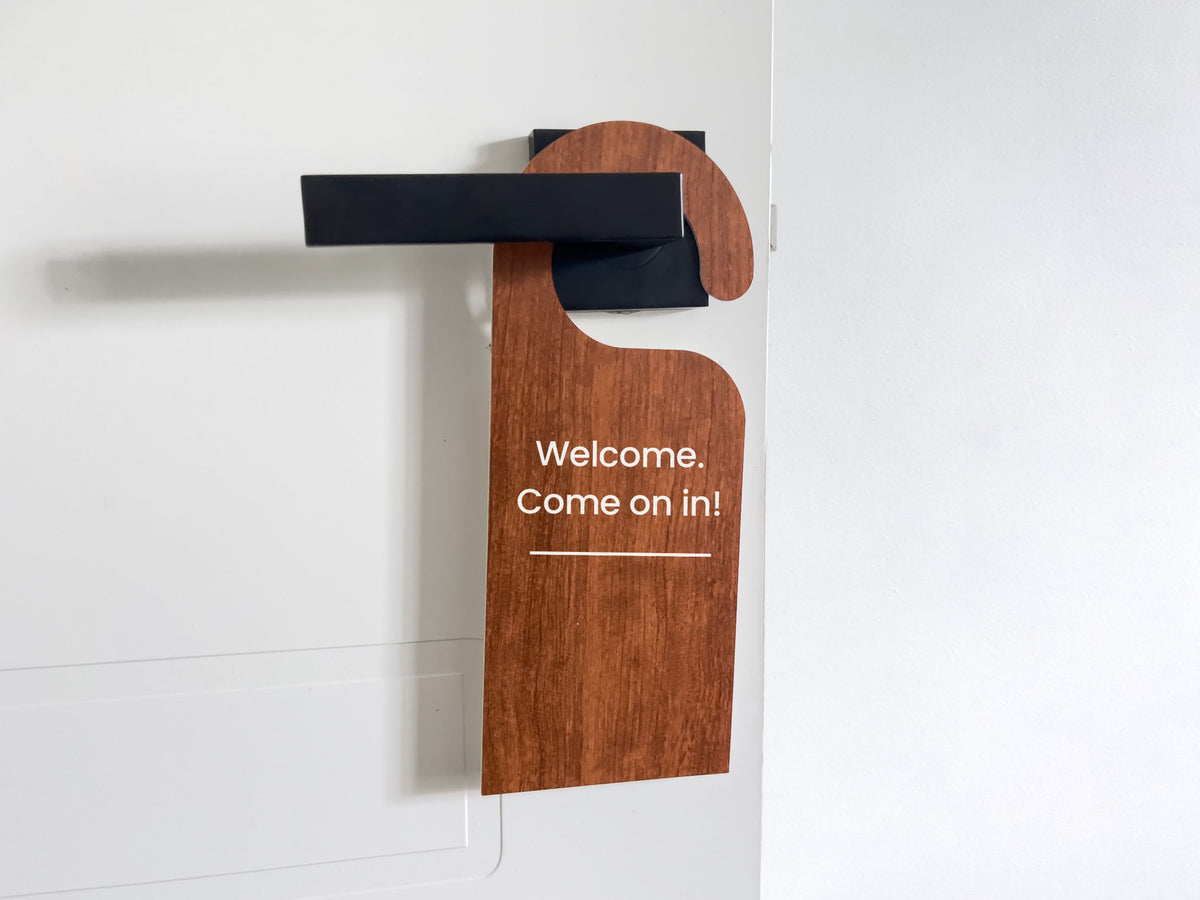 A flexi-plastic wood-look door hanger that reads 'Welcome. Come on in!'.