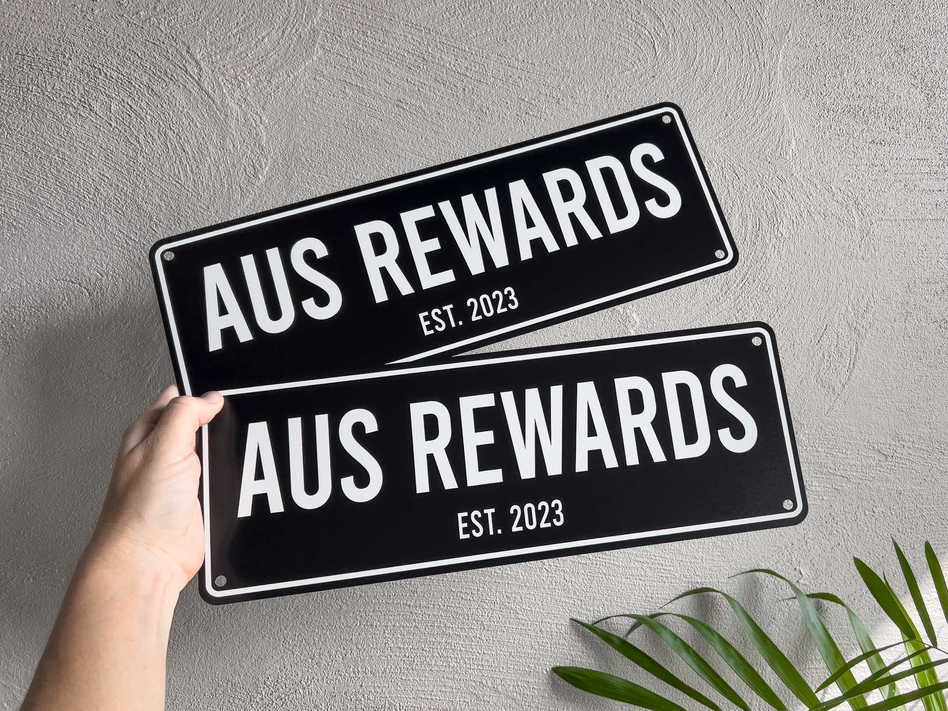 Two black and white custom text signs that read 'AUS REWARDS EST. 2023'.